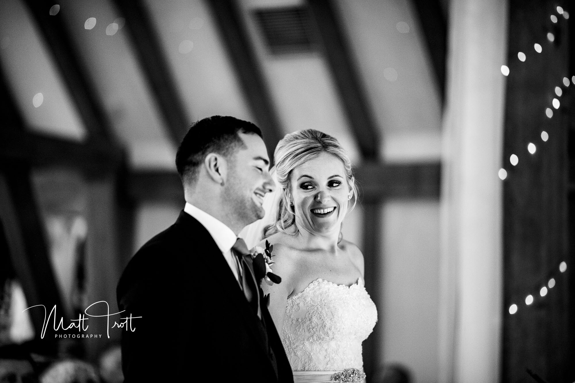 Bride smiling at the groom at their ceremony at the old kent barn