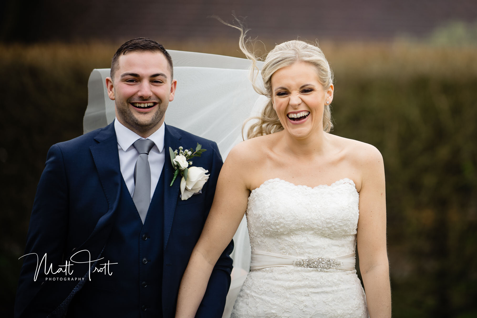 Bride and groom laughing in the bad weather at the old kent barn