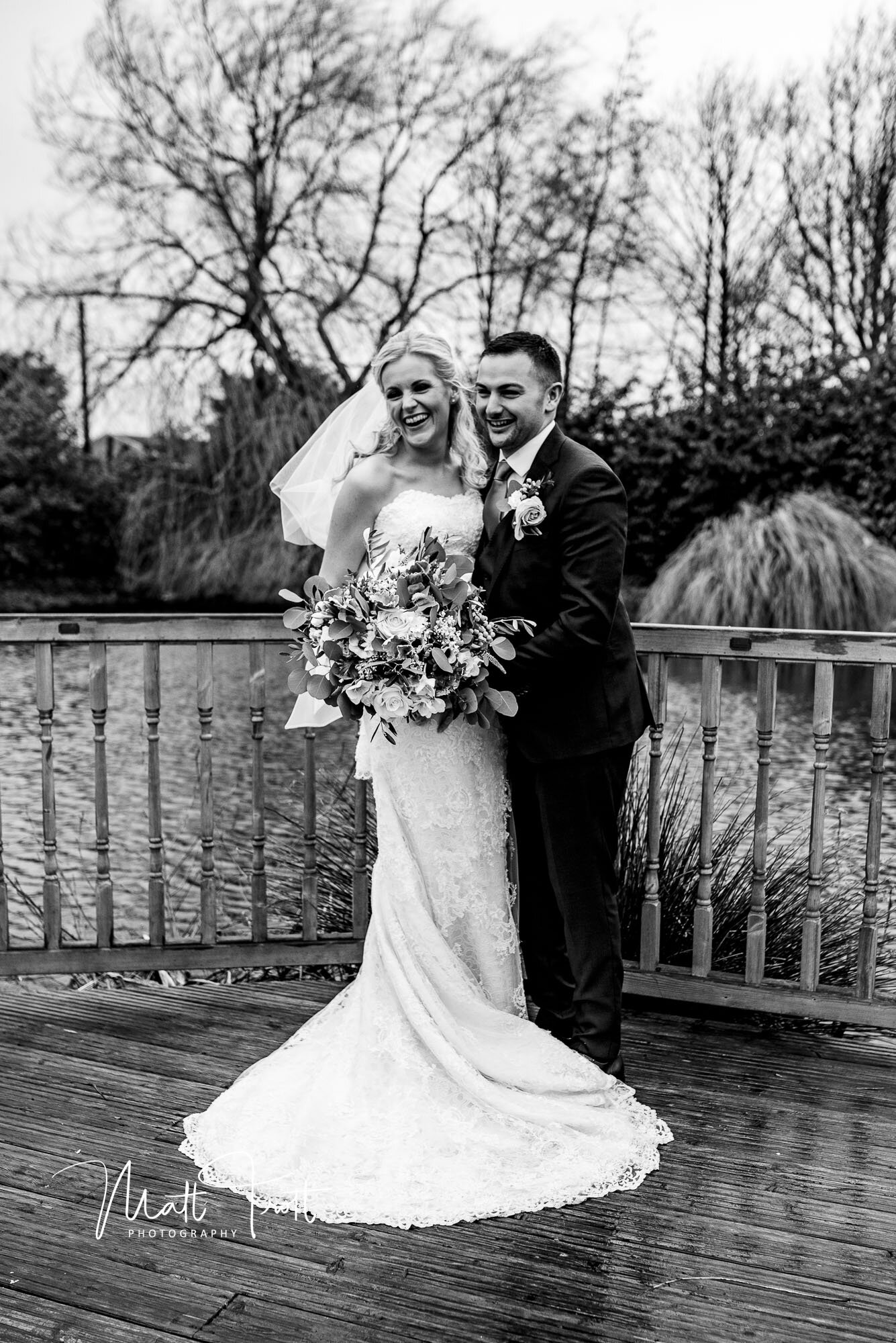 Bride and groom embracing at the pond at the old kent barn