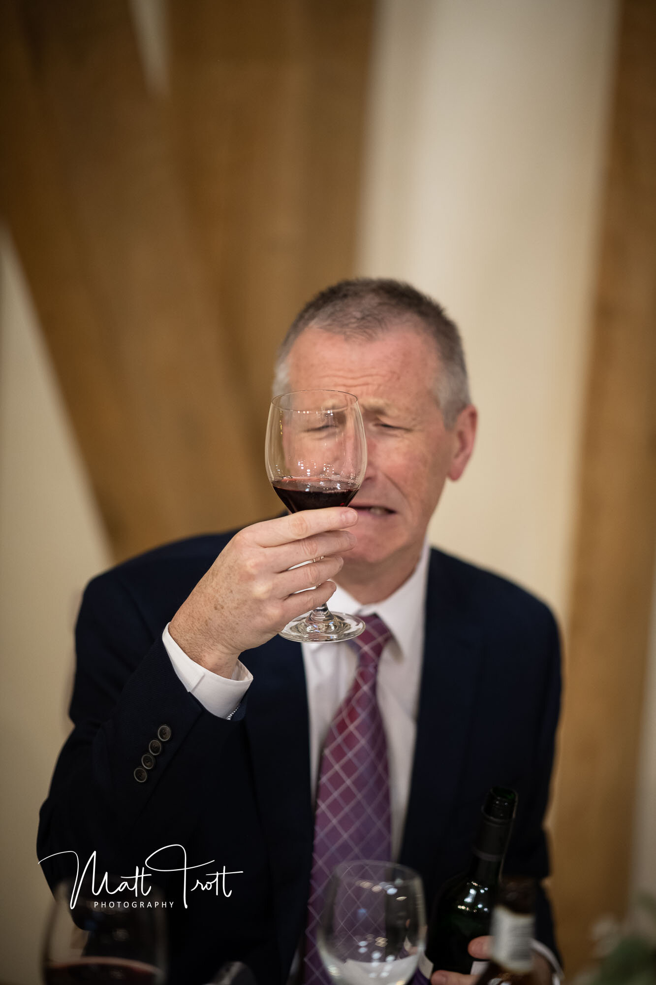 Guest making funny face into his wine at the old kent barn wedding venue