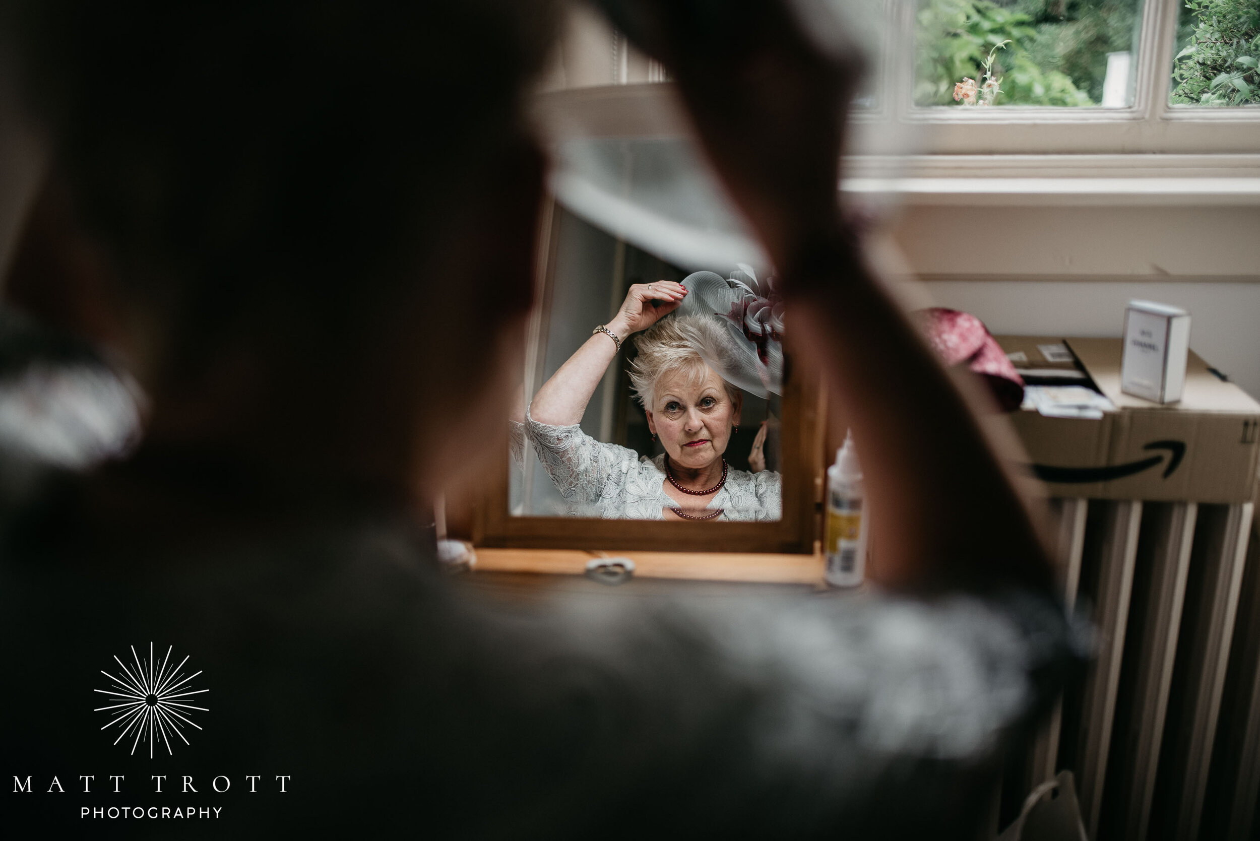 mother of the bride putting hat on at bradbourne house