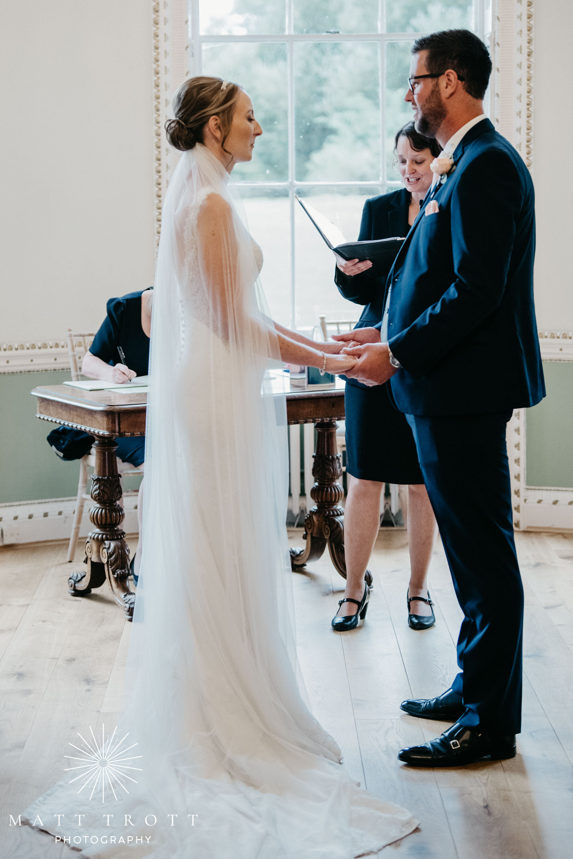 bride and groom exchanging rings in the ceremony room at bradbourne house