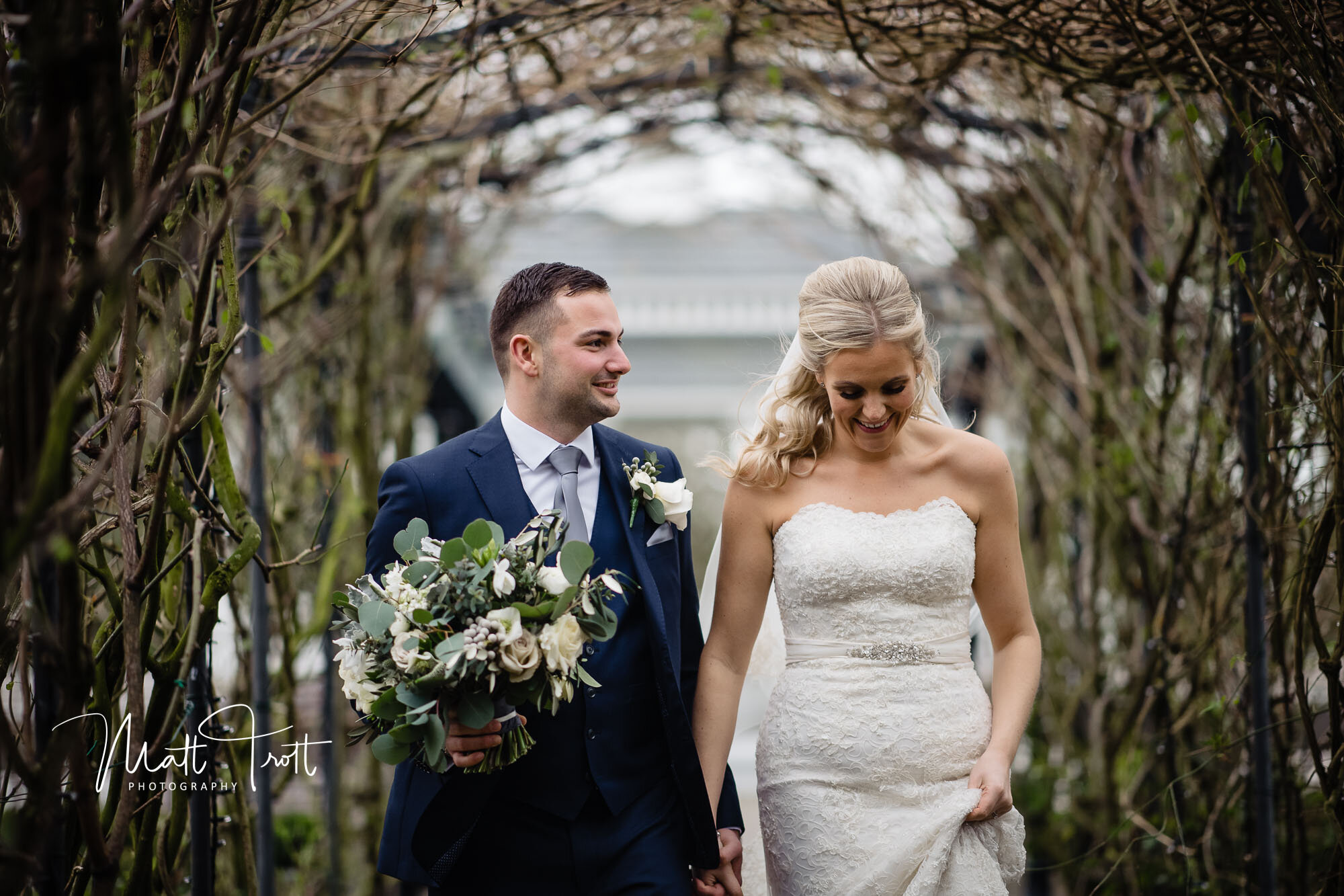 bride and groom walking through rose arch at the old kent barn