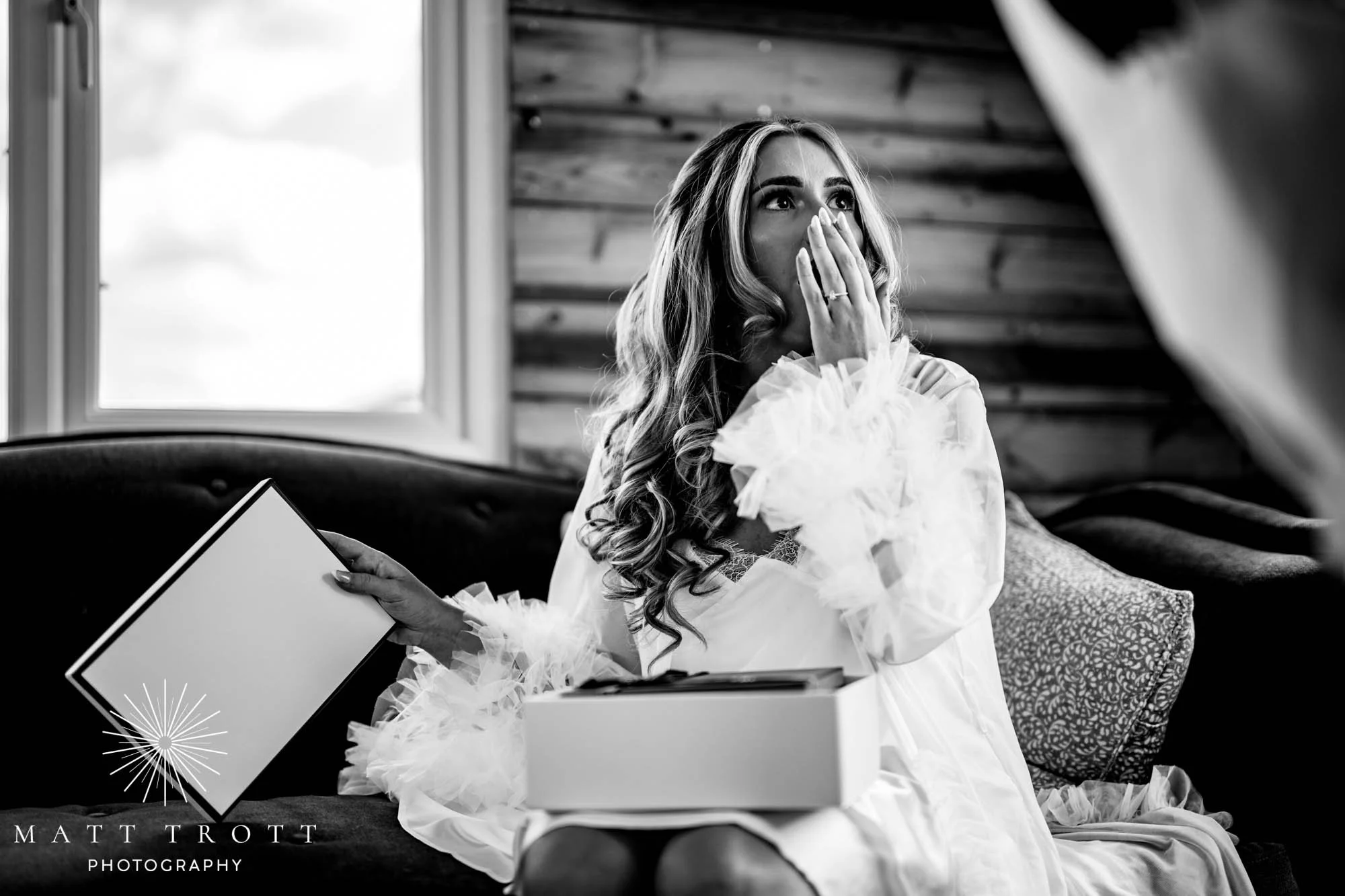 Bride with a shocked expression and hand over her face as she opens her gift from my fiance
