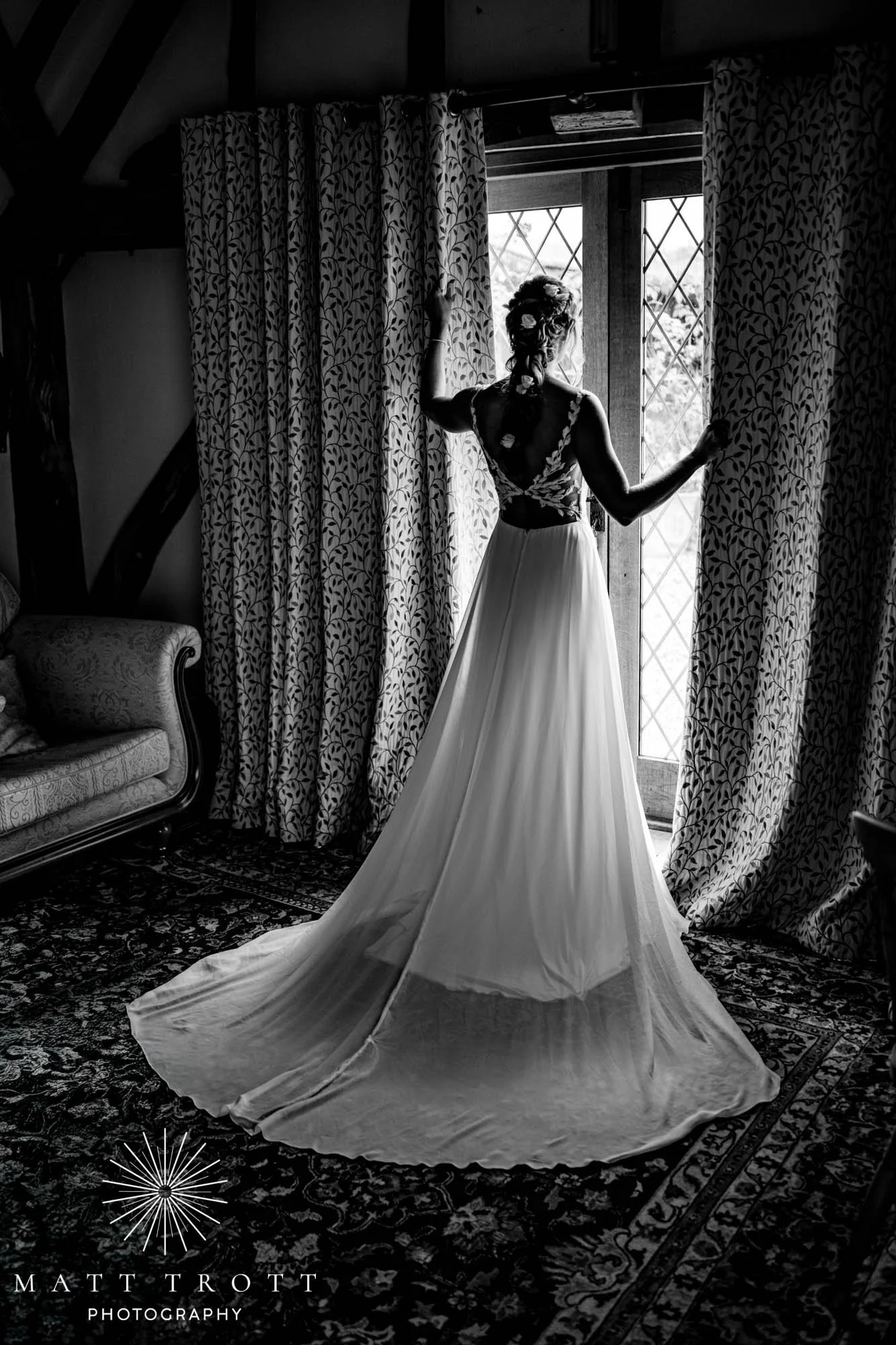 Bride in front of the window looking out holding the curtains