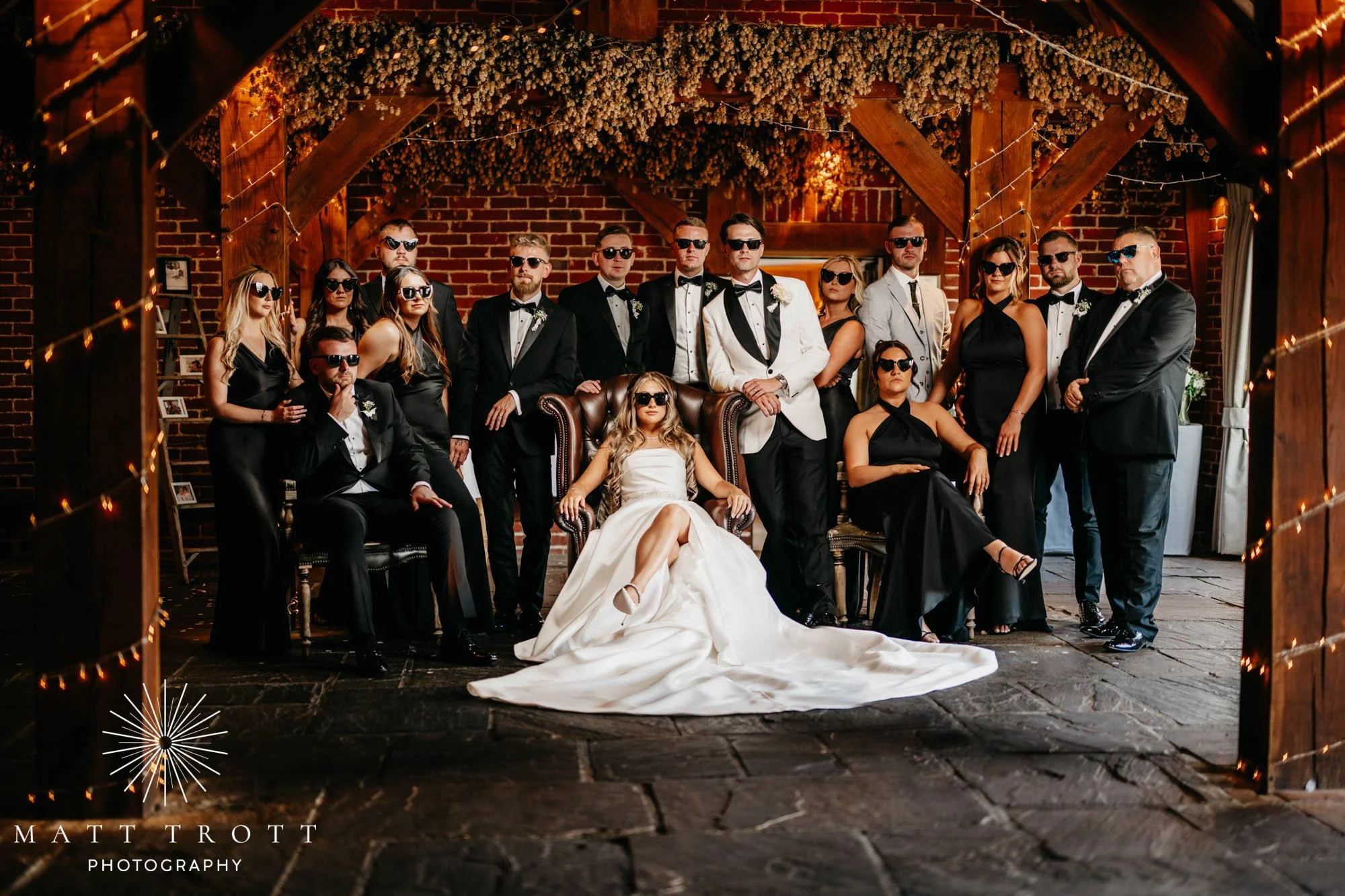 Bride and Groom surrounded by bridesmaids and groomsmen all wearing dark sunglasses at the ferry house in kent