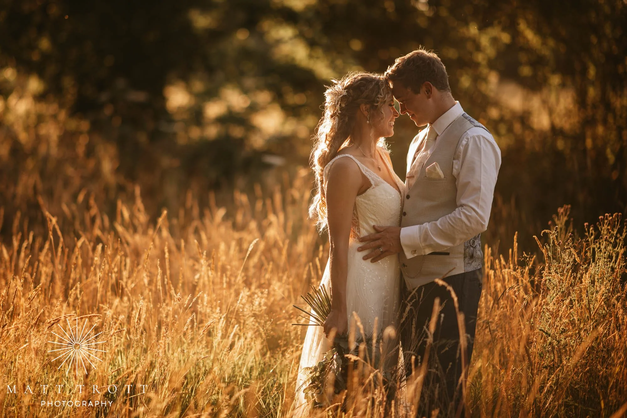 Bride and groom in long gras with heads close together