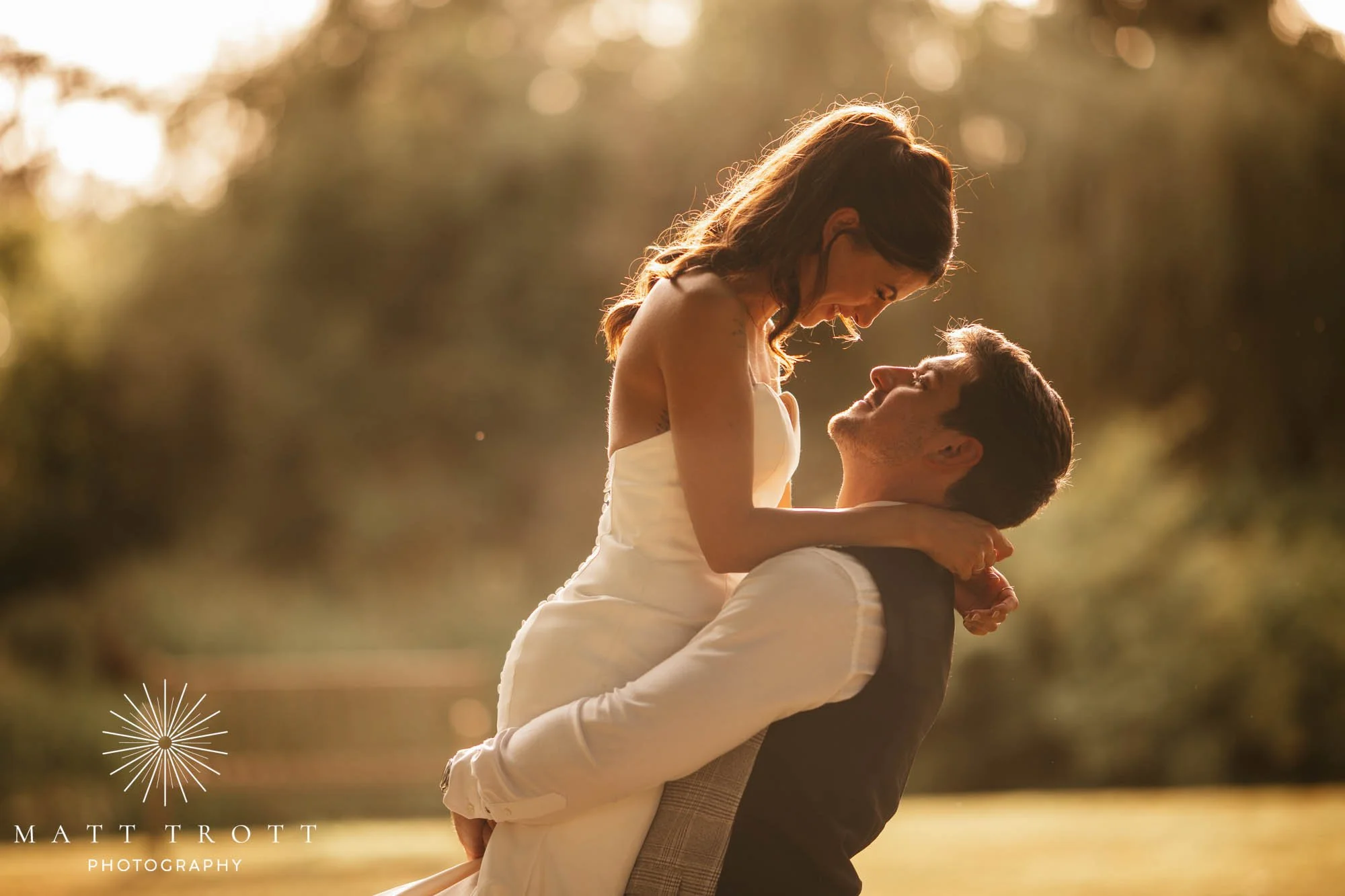 Bride being lifted into the air by her groom as they look into each others eyes