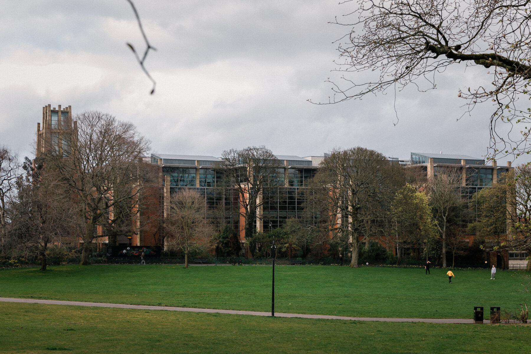 Three people socialise at a distance, on a normally thronged central green in Botanic Gardens, Belfast