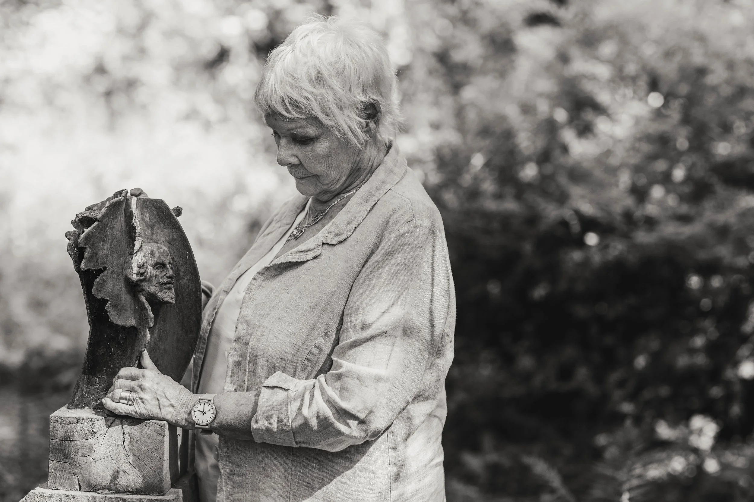 Dame Judi Dench in her garden with an award sculpture depicting the head of William Shakespeare
