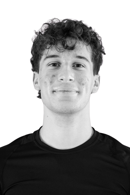 Black and white portrait of a young man with curly hair, smiling and wearing a dark jacket.