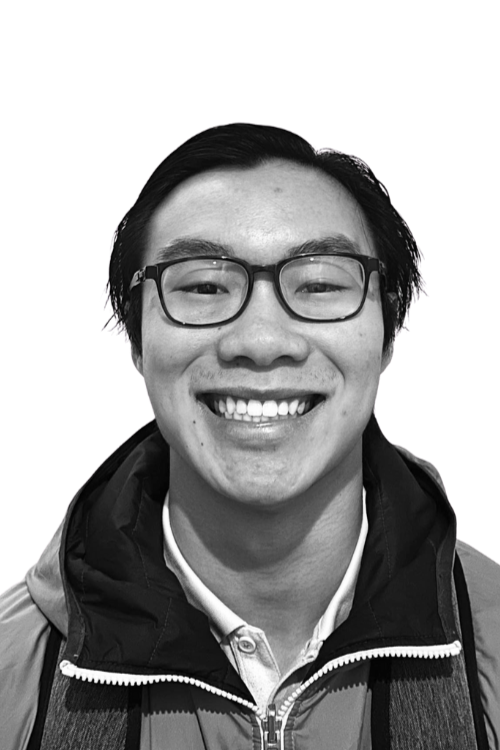 Black and white portrait of a young woman smiling, with wavy dark hair, wearing earrings and a necklace.
