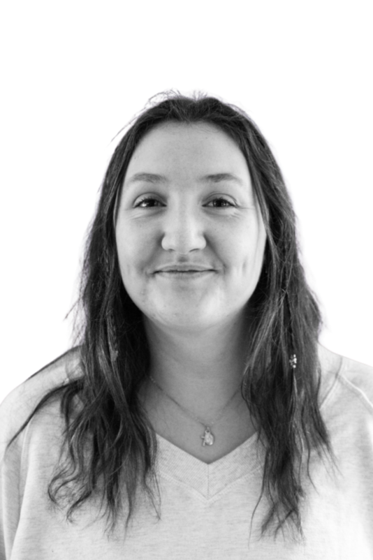 Black and white portrait of a young man with curly hair, a mustache, and a beard, smiling and wearing a hoodie and jacket.