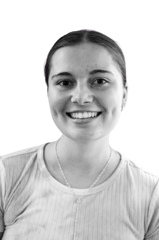 Black and white portrait of a young man smiling at the camera, wearing a light-colored shirt and necklace, against a plain background.