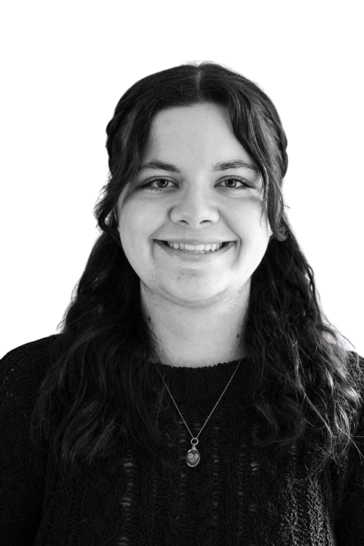 Black-and-white photo of smiling young man with short hair, wearing a collared shirt, against plain background.