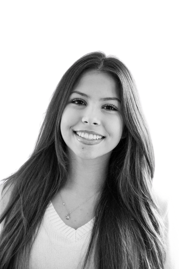 A young man with light-colored hair smiling in a black and white photo.
