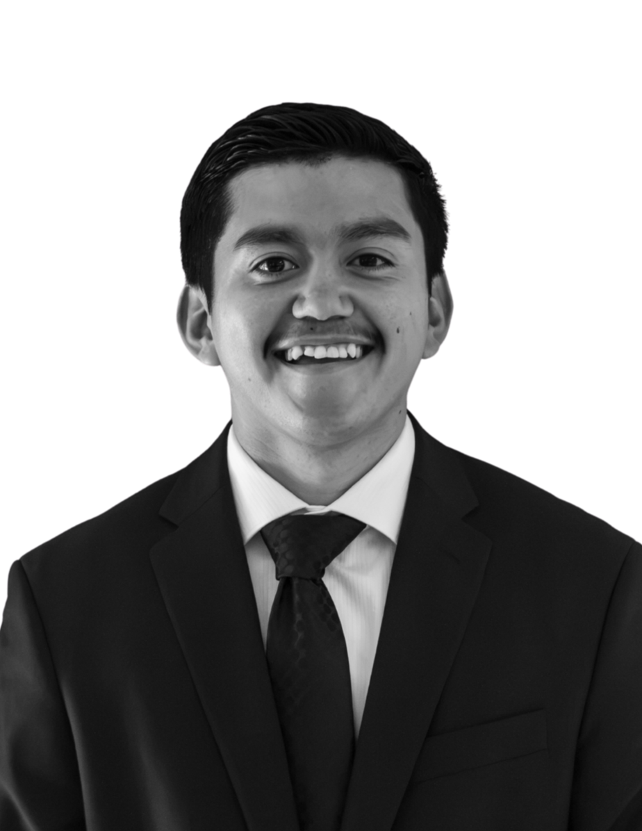 A black and white photo of a young man in a suit and tie, smiling, against a plain background.