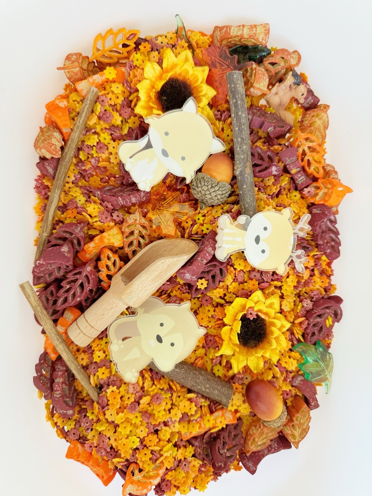 Autumn nature treasure bin with leaf-shaped pasta, acorns, twigs, sunflowers, and woodland animal cutouts