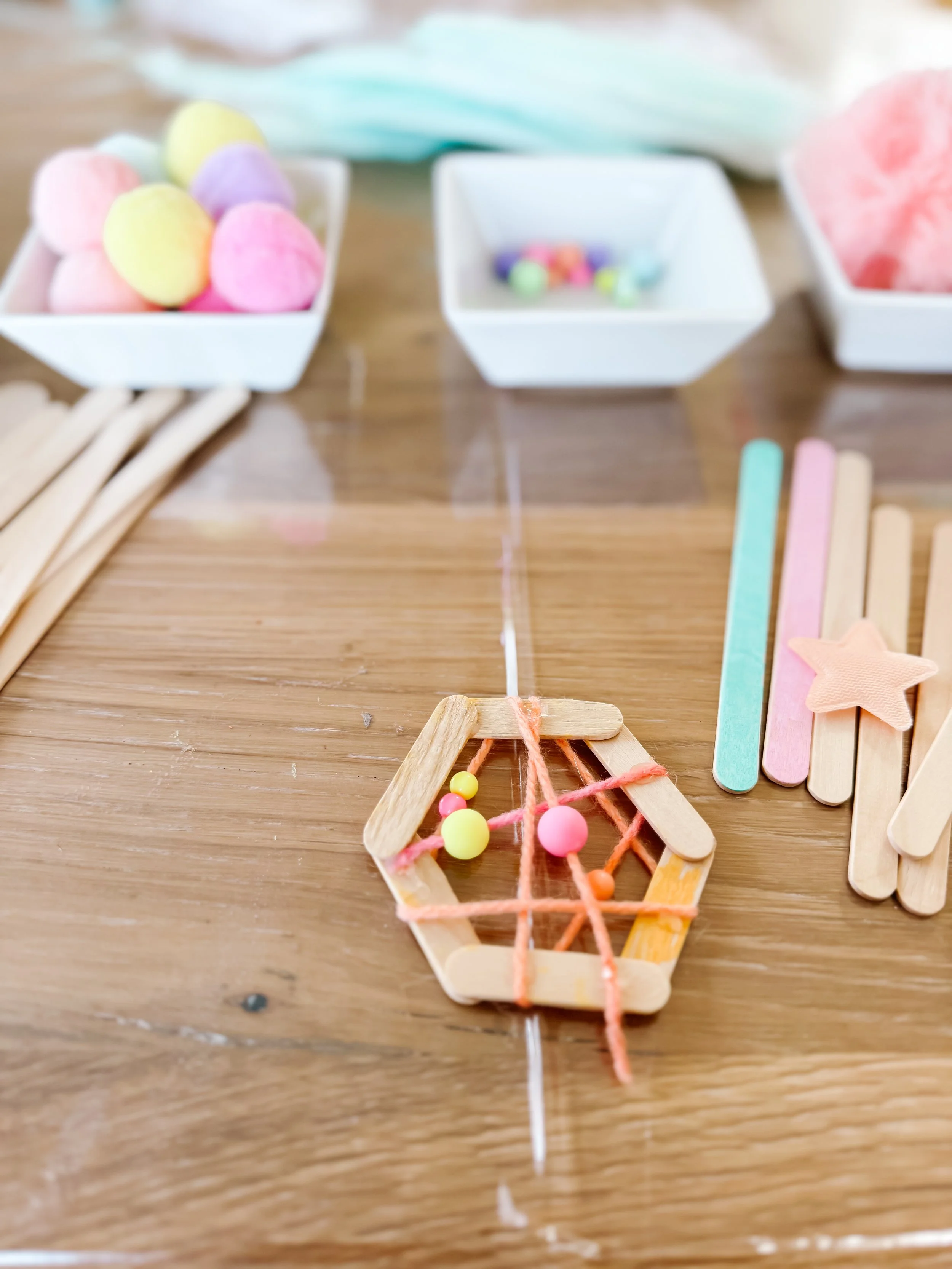 Small hexagonal craft-stick frame woven with coral yarn and decorated with pastel beads.