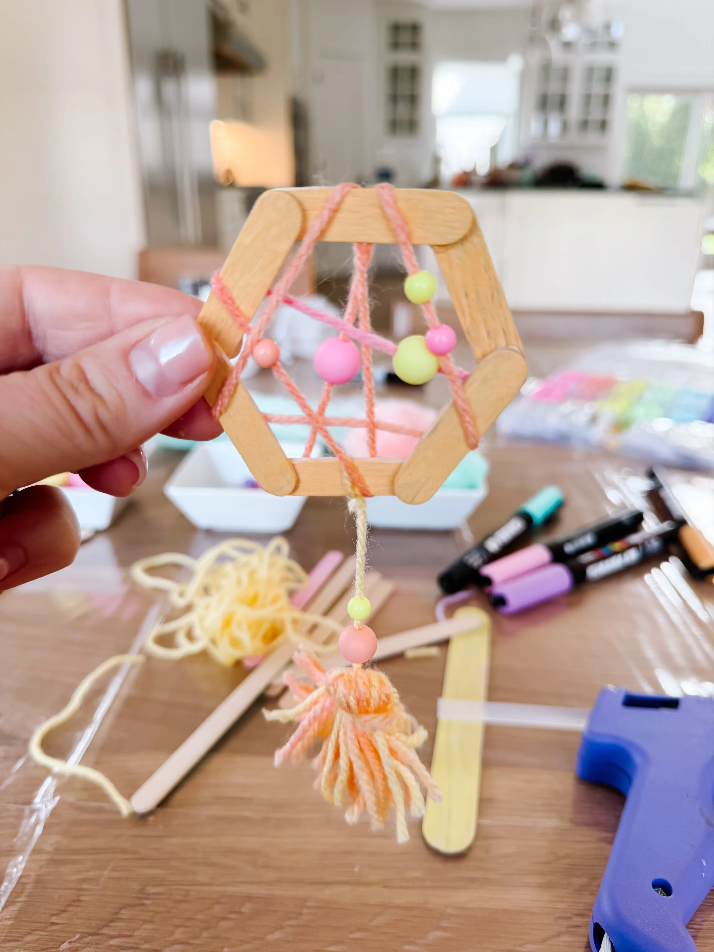 Finished hexagonal yarn web with pastel beads and a hanging yarn tassel.