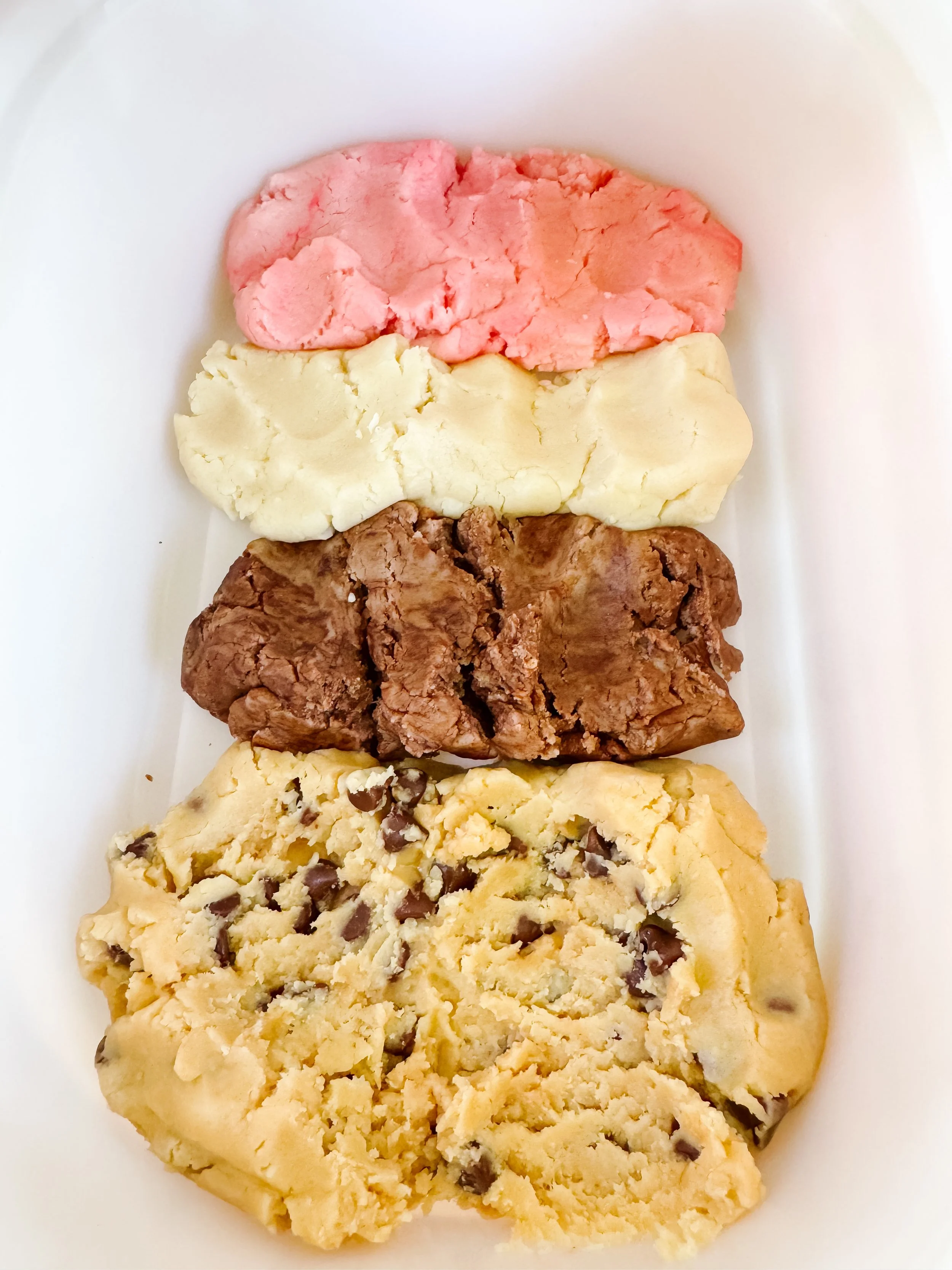 Colorful ice cream play dough flavors arranged in a bin for mud kitchen play.
