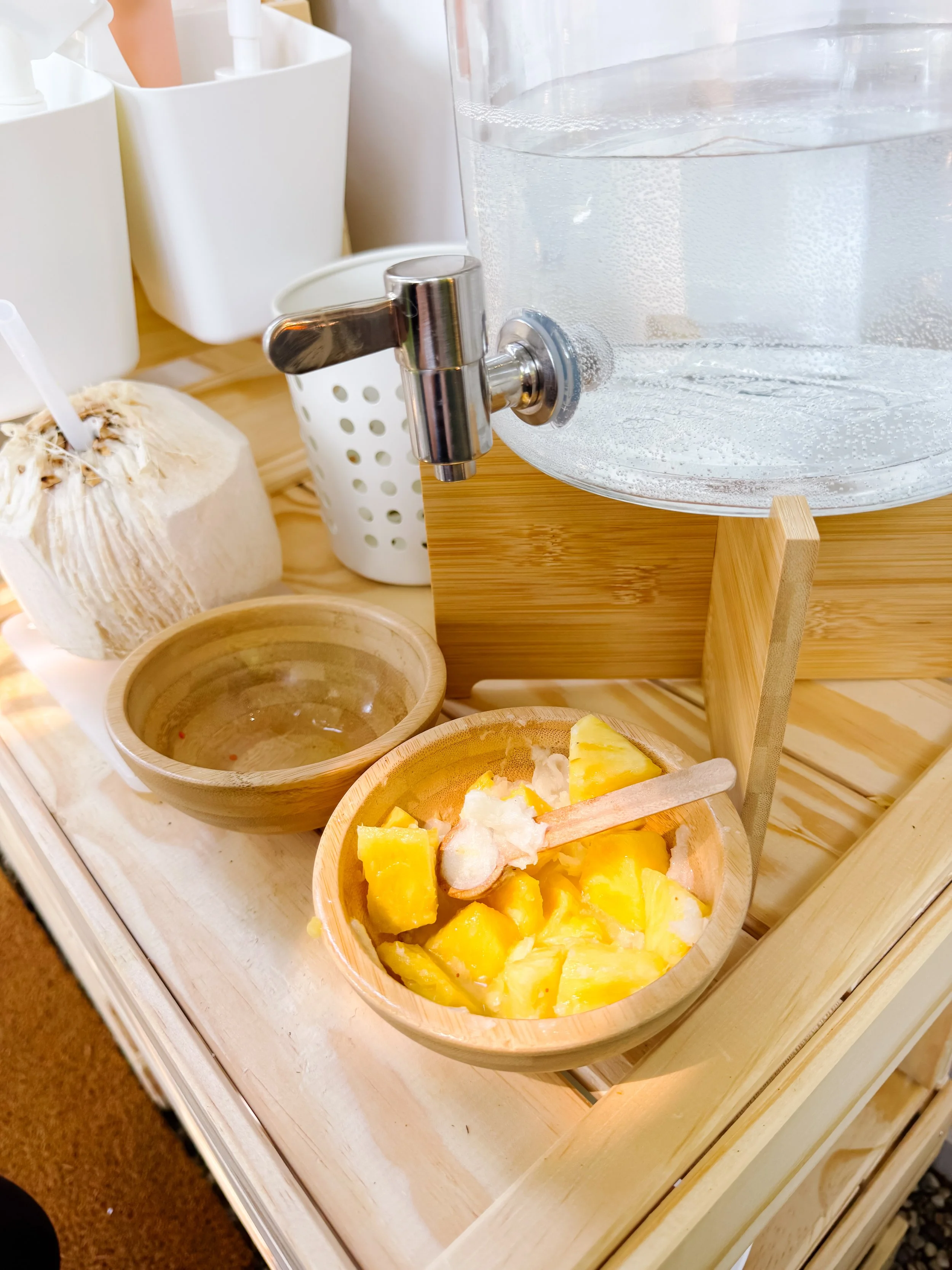 Pineapple and coconut ingredients in small bowls for smoothie mud kitchen play.