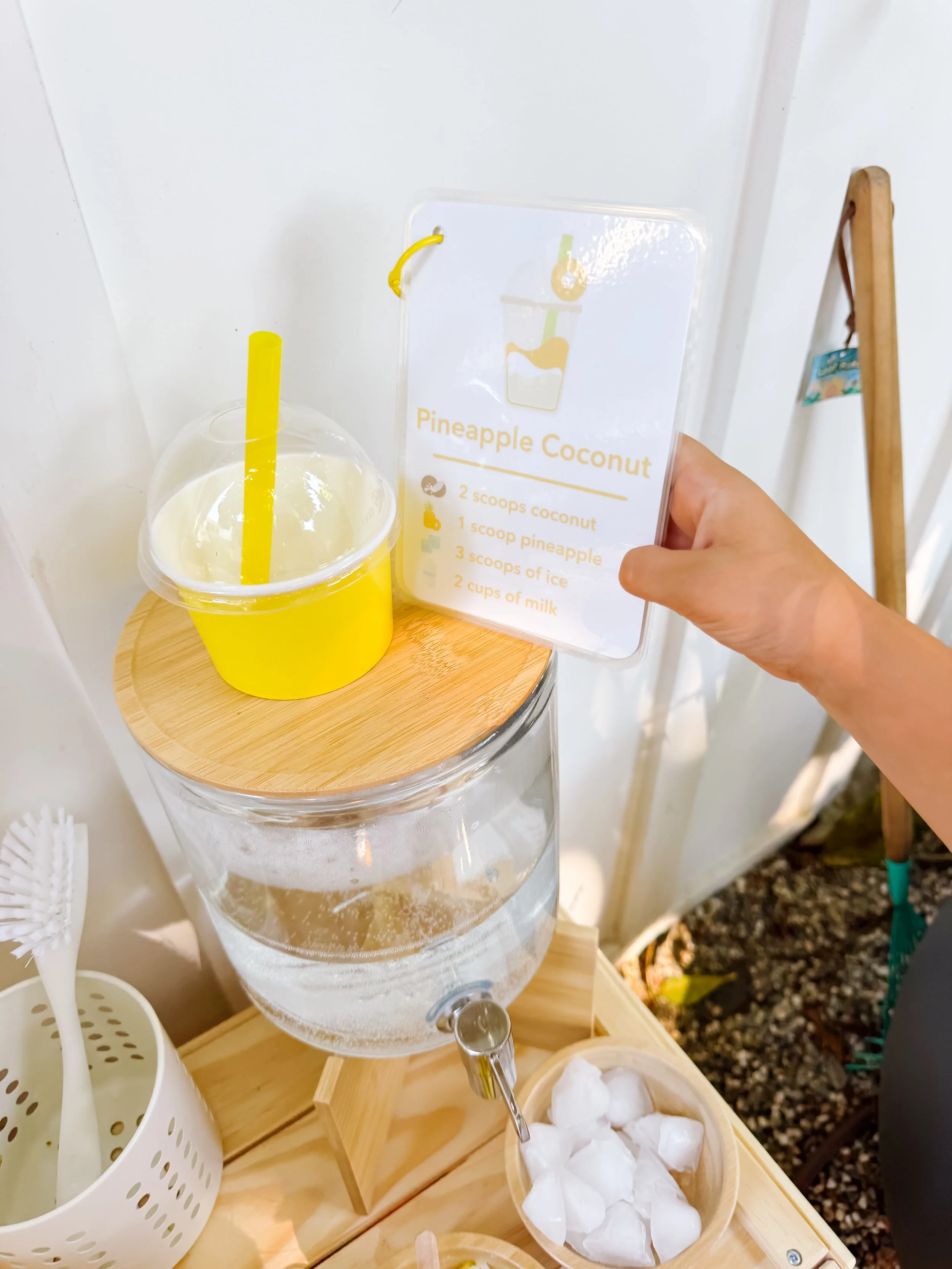 Pretend pineapple coconut smoothie served in a yellow cup with recipe card.