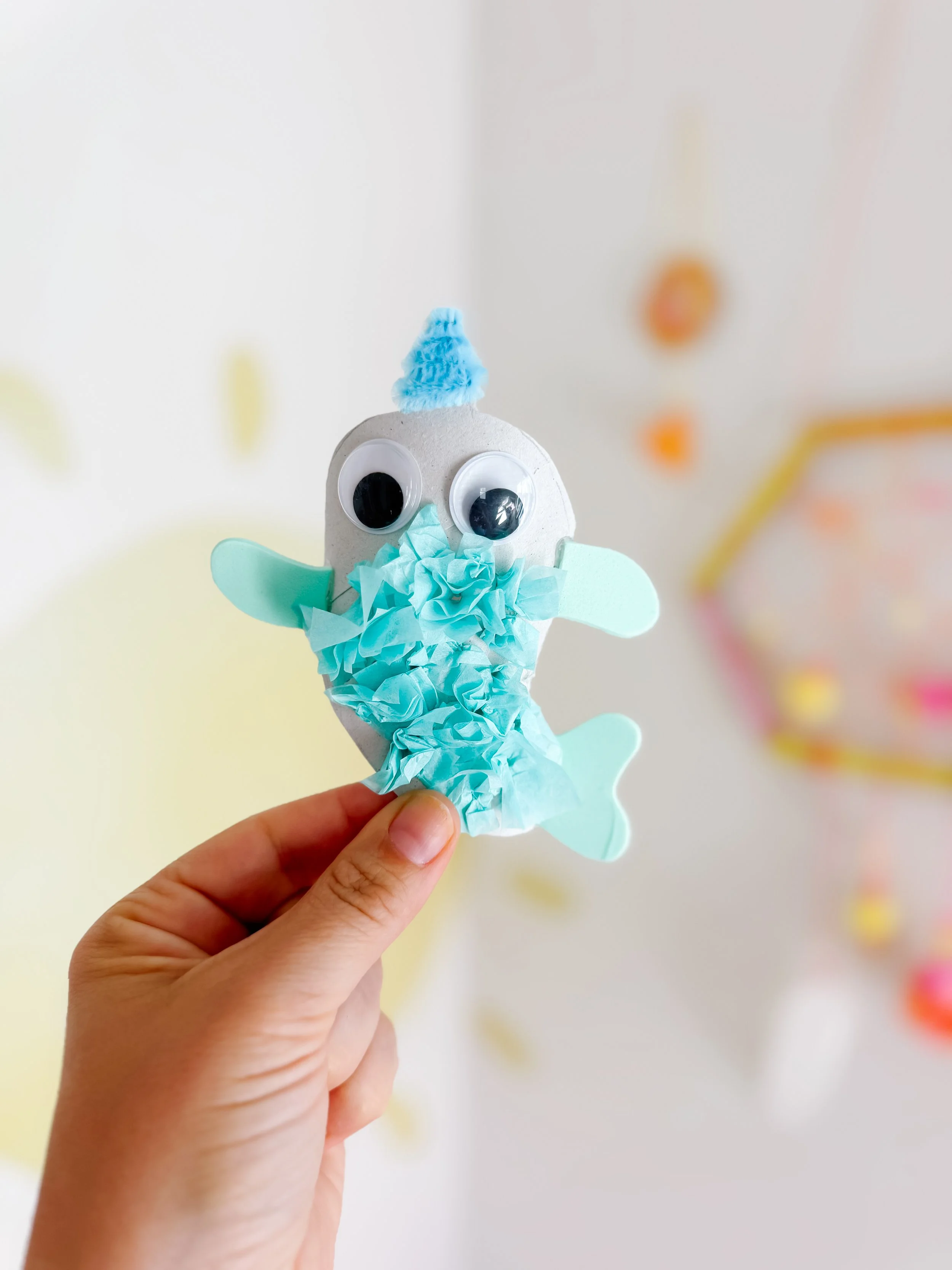 Child holding a completed blue toilet roll narwhal craft.