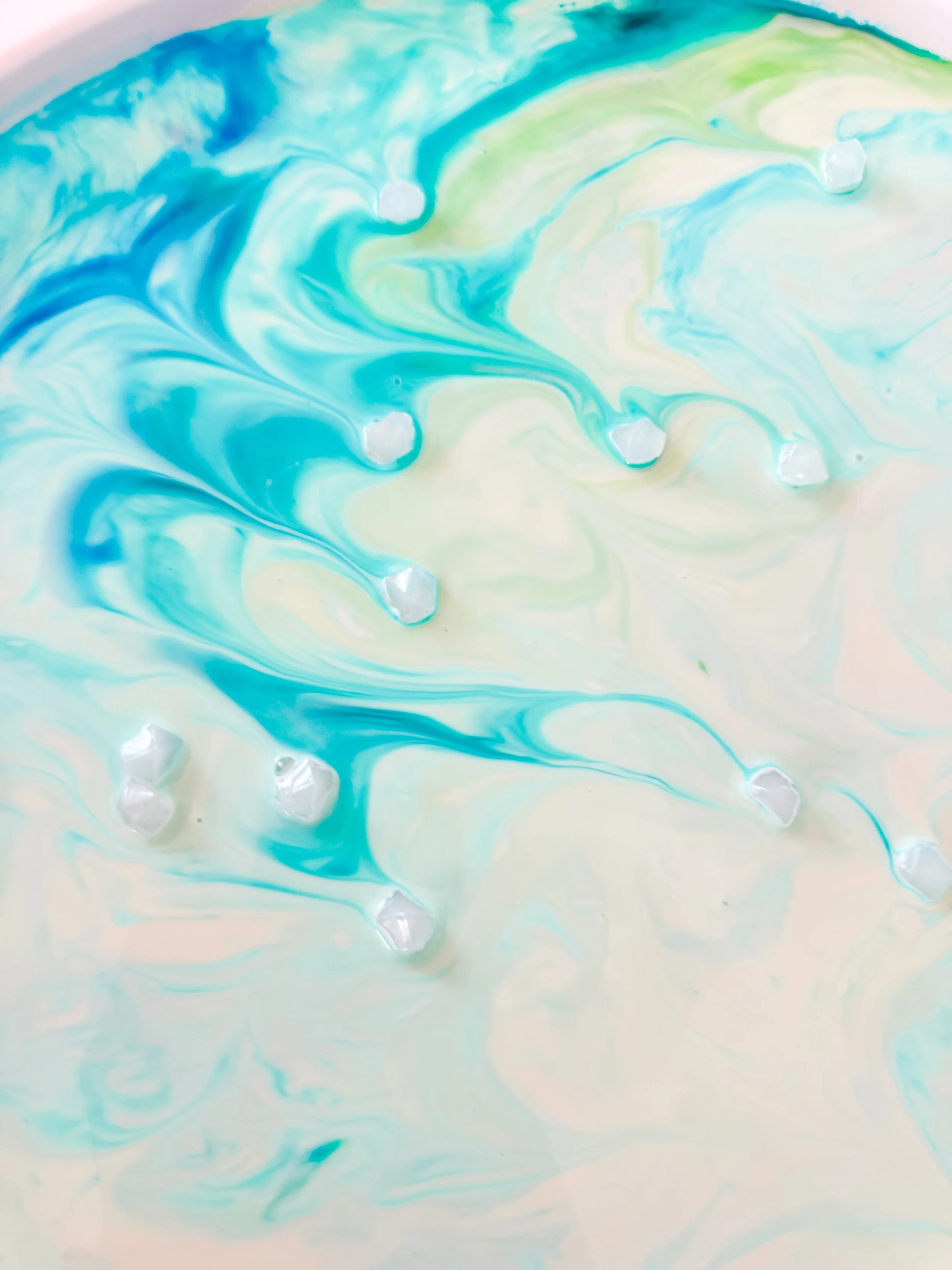 Close-up of turquoise Northern Lights Magic Milk ribbons flowing around clear acrylic gems.