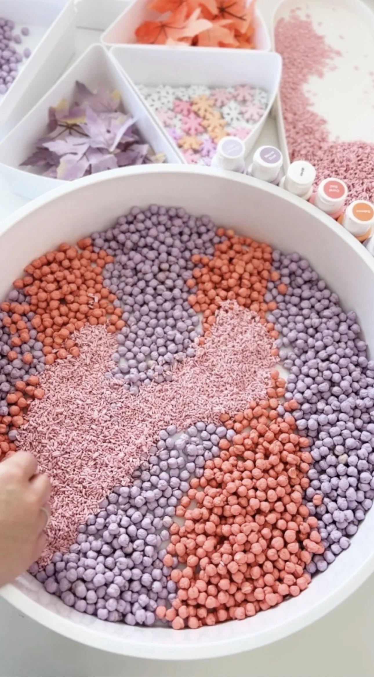 Pastel fall frozen sensory bin with dyed chickpeas and pink rice in a white tray