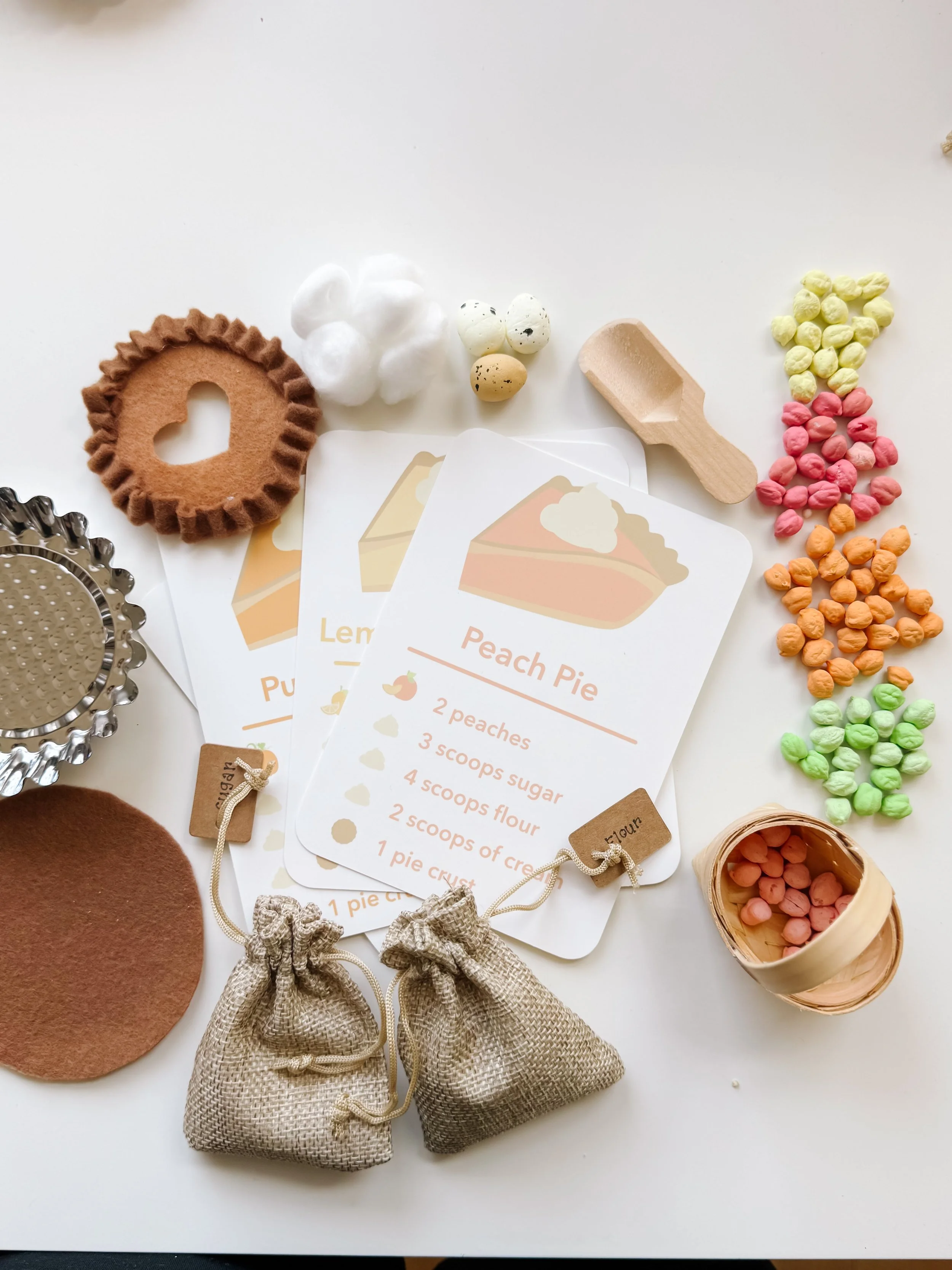 Pie Making Sensory Kit laid out flat: pie recipe cards, felt pie crust, metal pie tin, colored chickpea fillings, wooden scoop, foam eggs, and burlap sugar and flour bags