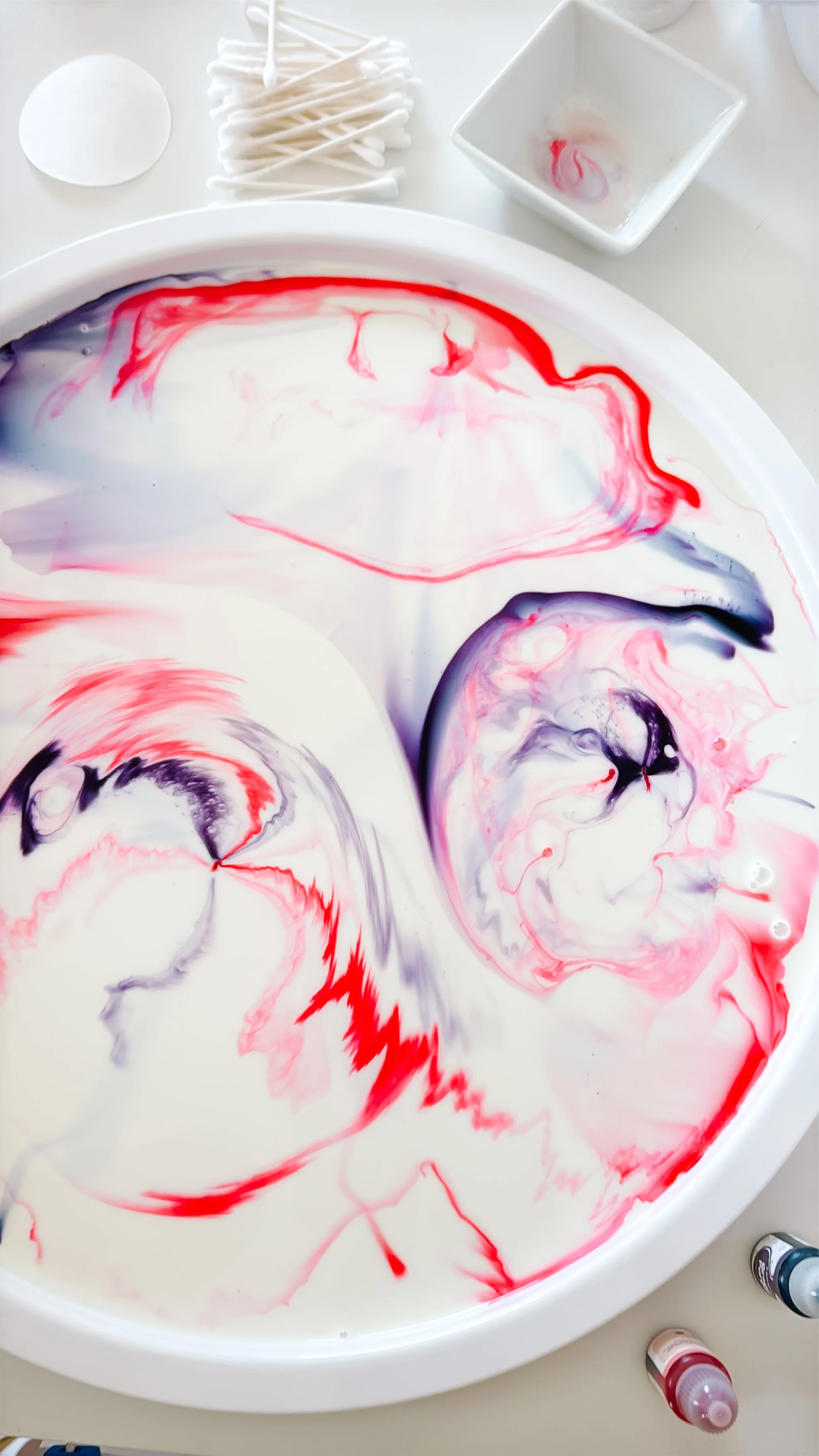 Pink and purple color patterns spreading across milk during a unicorn science experiment.