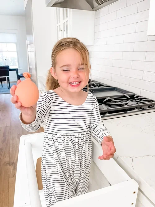 Toddler squeezing DIY stress ball for fine motor development