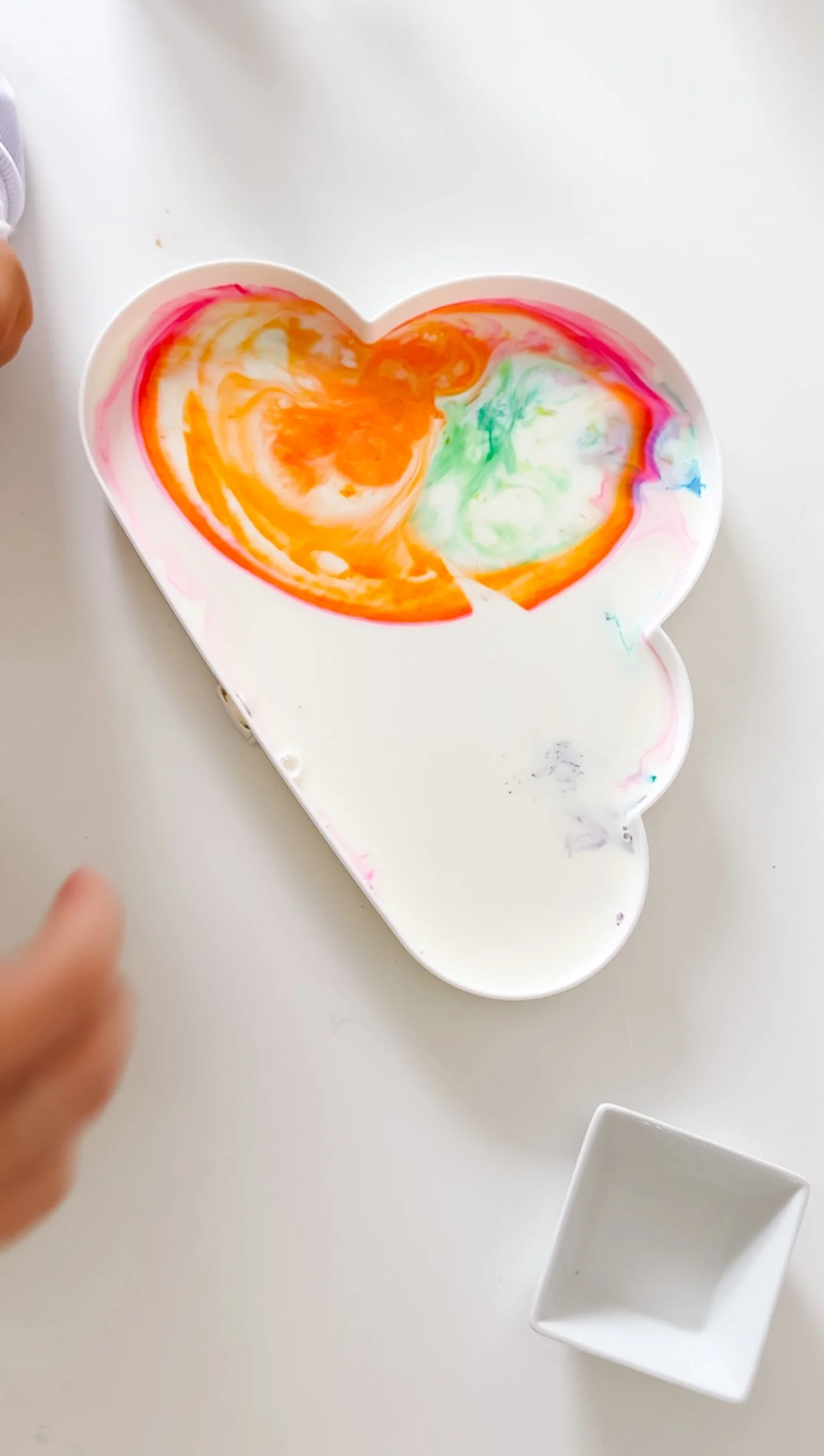 Drops of rainbow food coloring in milk for a preschool STEM experiment.