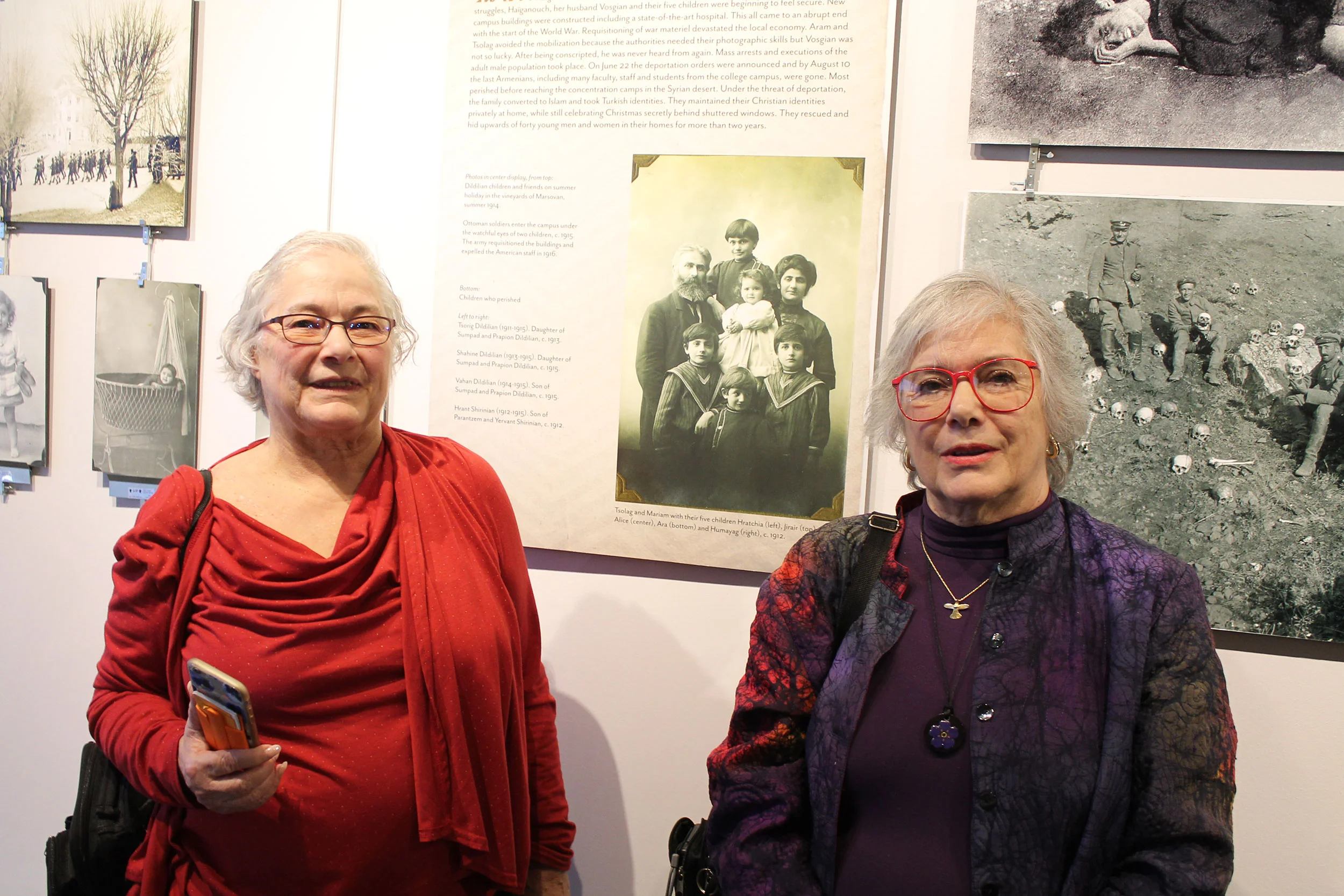 Two daughters of the Dildilian family posing with a portrait featuring their father as a child