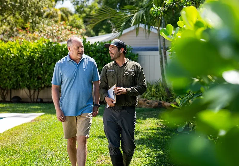 Mosquito control technician walking through backyard with homeowner during outdoor inspection