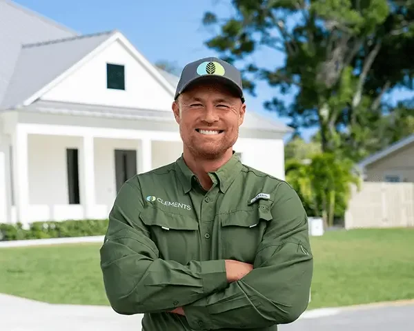 Clements Pest Control technician smiling in front of a Vero Beach home