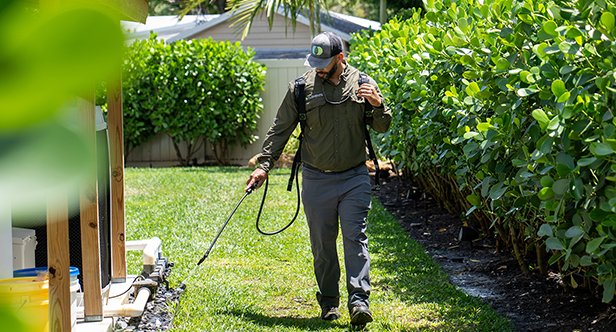 A technician spraying the exterior of a home for pests.