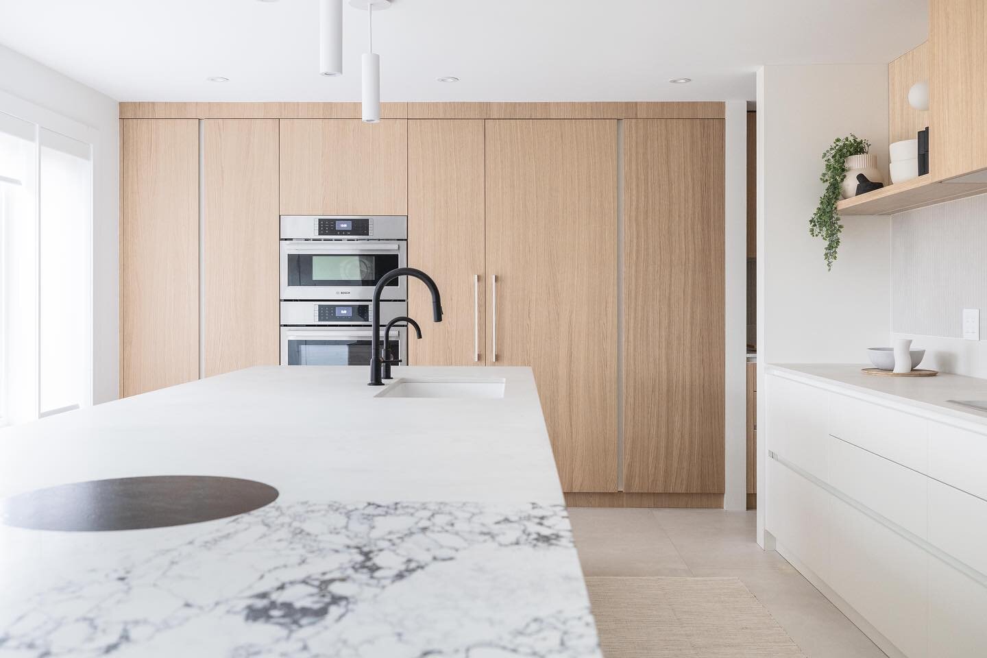 It&rsquo;s all about the art of the kitchen layout! We used the windowless back wall as floor-to-ceiling closed storage for the fridge, ovens and pantries. The remainder of the kitchen is left airy and open for natural light to flow through. The isla