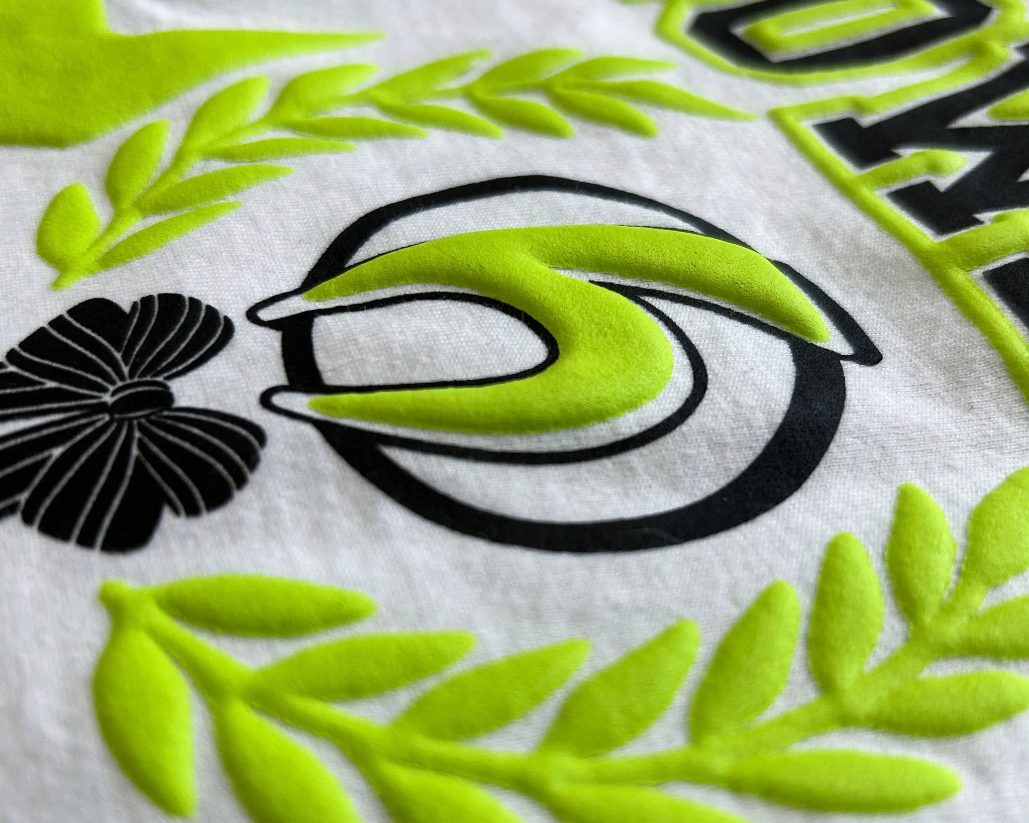 Close-up of a shirt design combining Puff ink with flat Howard Multi-Purpose ink, showcasing a premium specialty finish with dimensional detail.