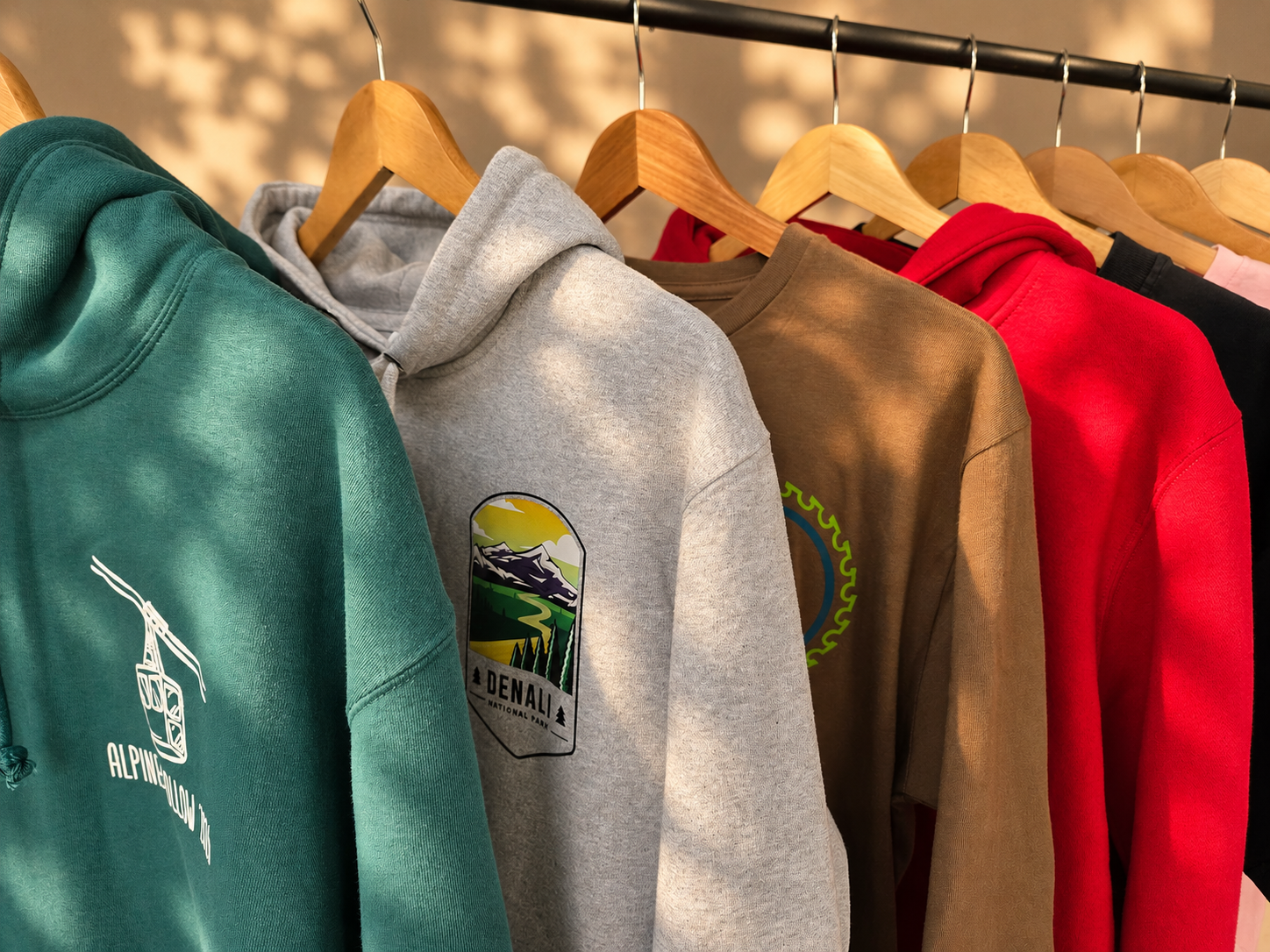 Editorial rack of decorated Lane Seven hoodies and sweatshirts in teal, heather gray, toasted coconut, red and black for the Holiday Merch Edit collection