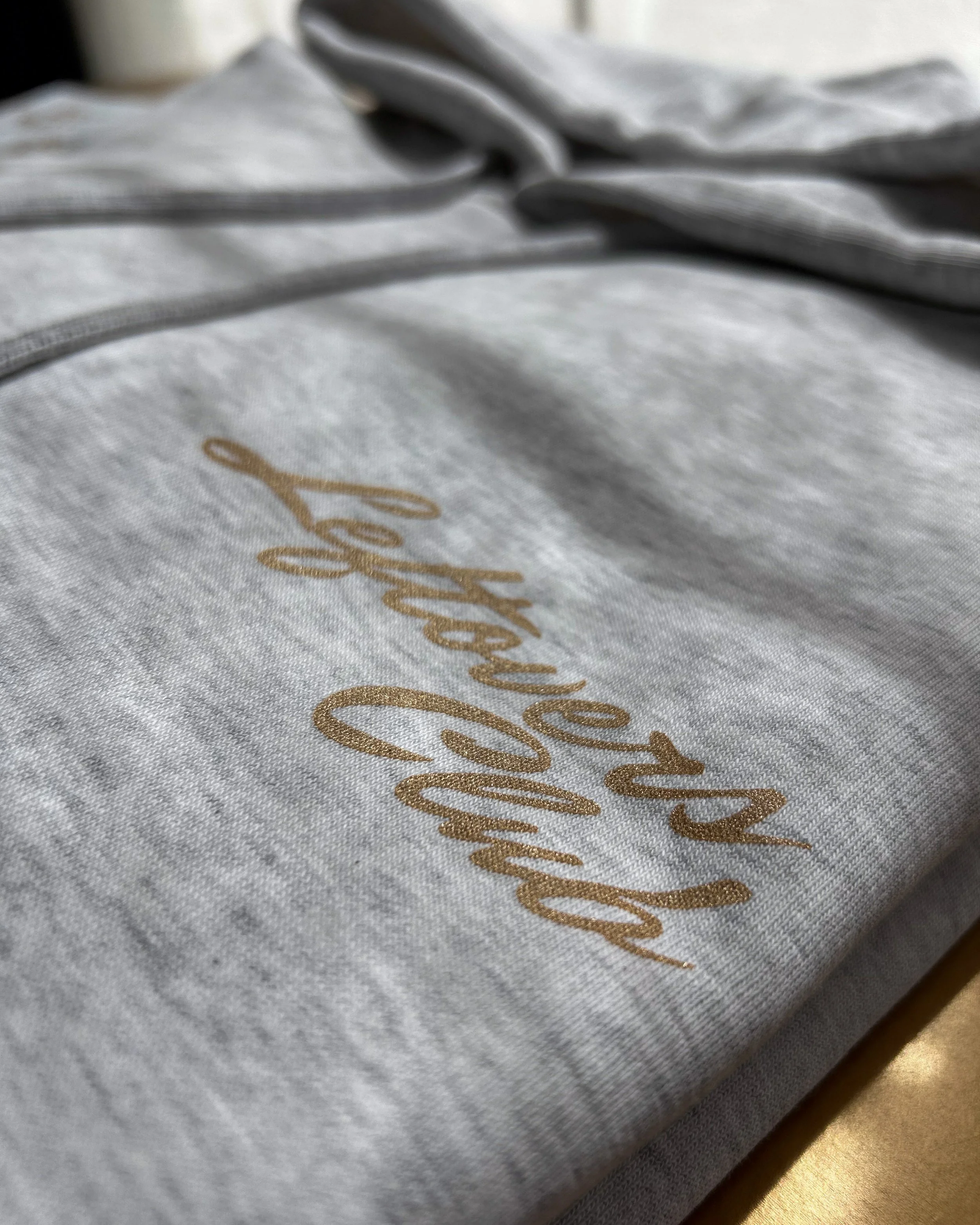 The Leftovers Club script printed with Howard Hot Peel in Copper Shimmer on an ash grey Stanley/Stella hoodie.
