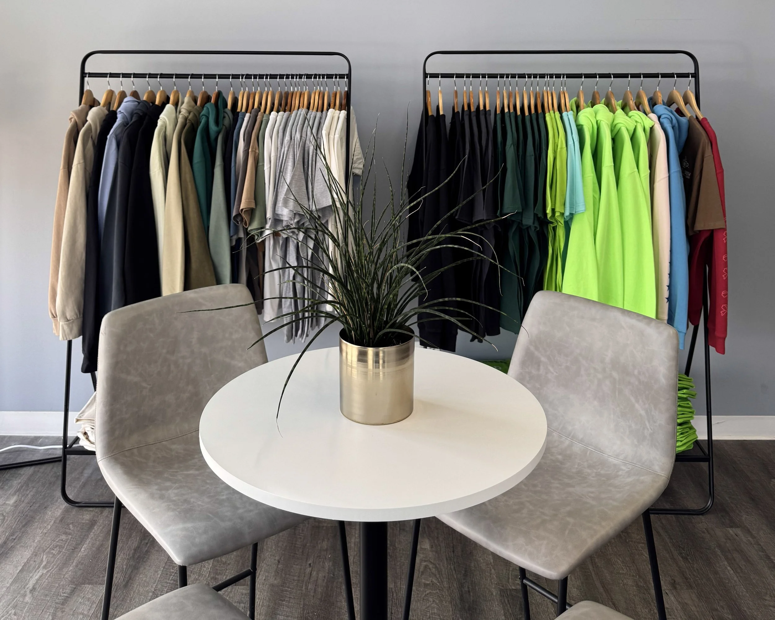 Well-organized apparel decorator showroom displaying sample garments, including shirts and hoodies, arranged to showcase design options and heat transfer finishes.