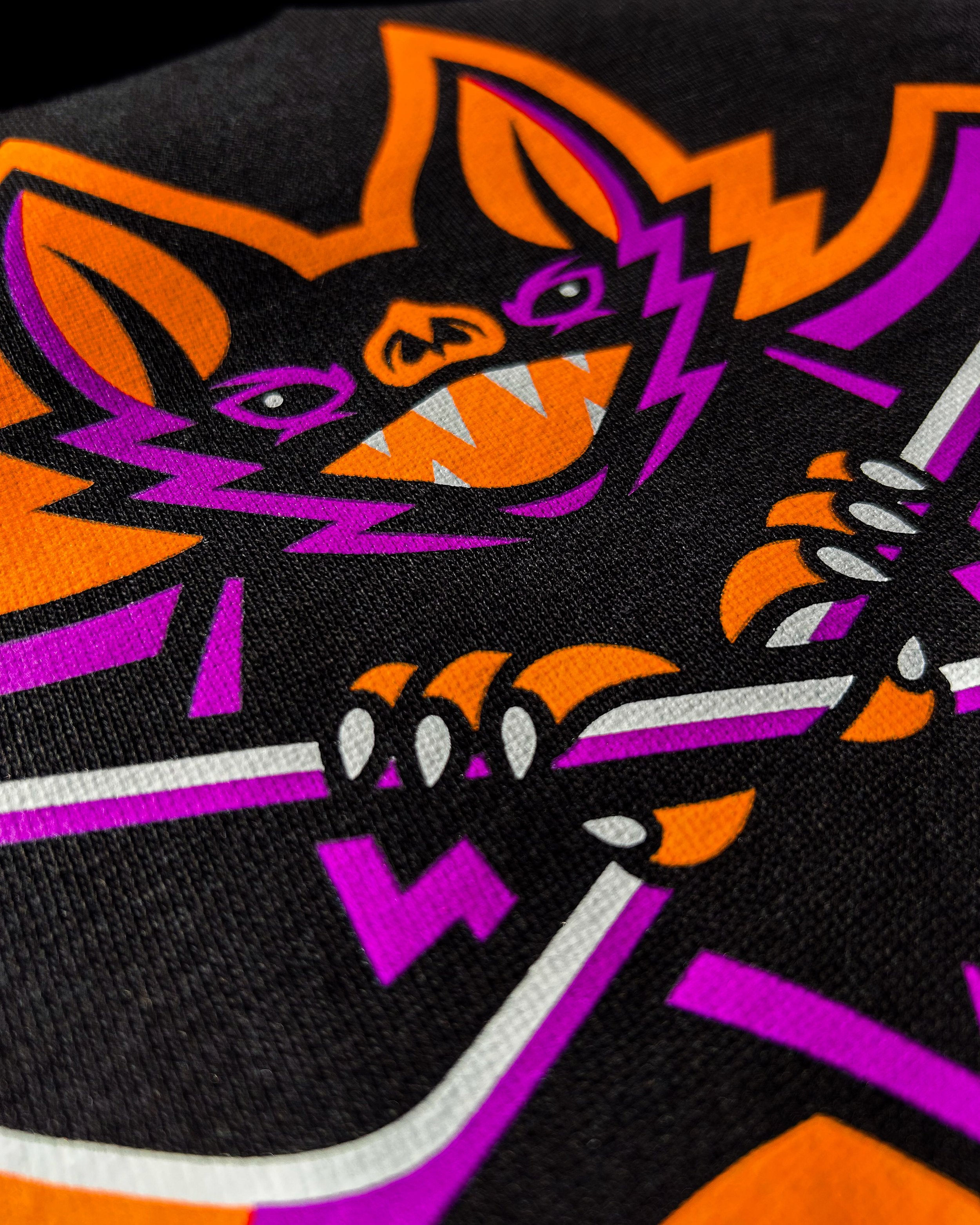 Close-up of the Night Flyers bat hockey graphic printed in Neon Orange, Neon Purple and White on a black hoodie.