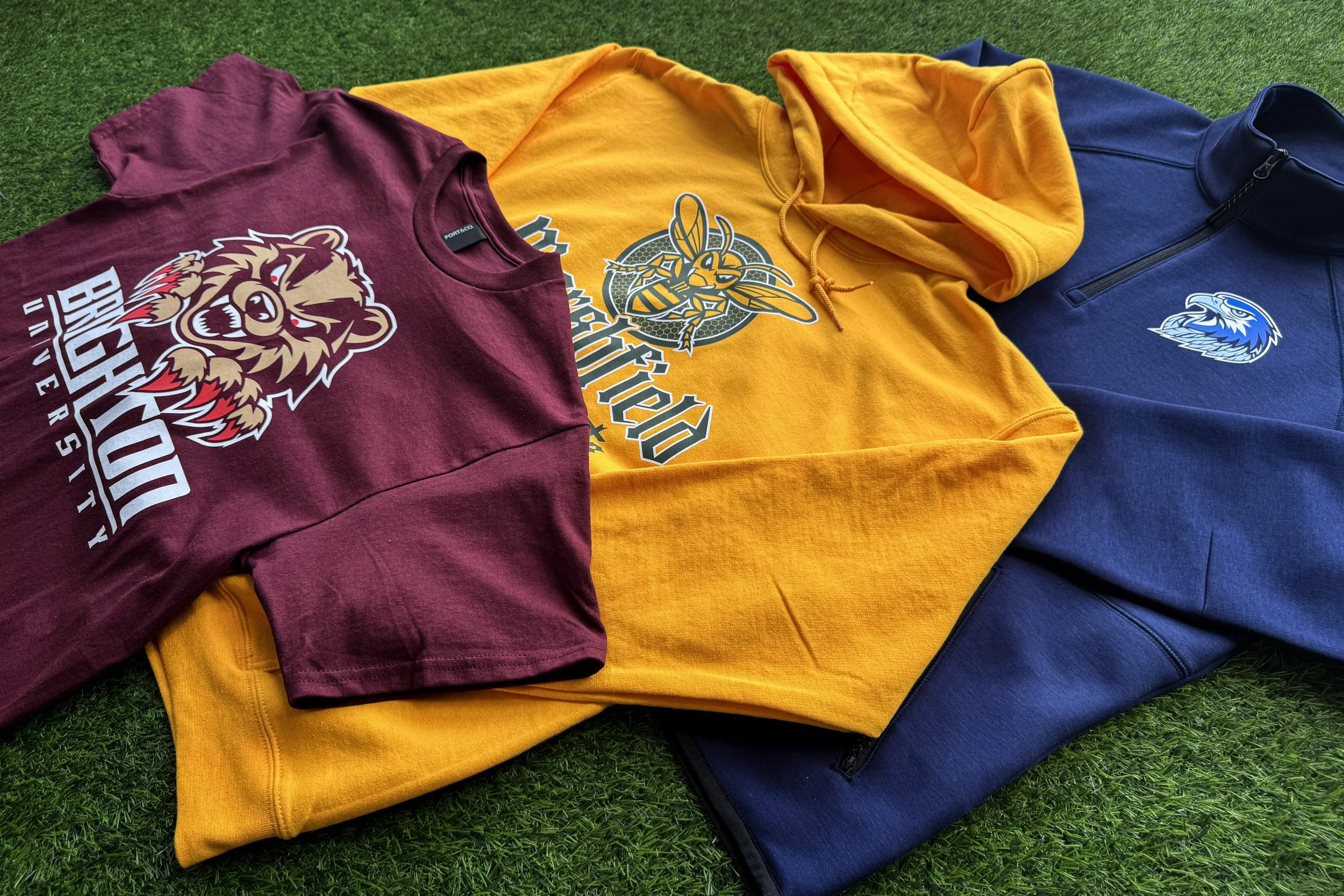 Three-piece Legacy Athletic school spirit wear collection featuring a heavyweight tee, hoodie, and quarter-zip decorated with Howard Hot Peel and Multi-Purpose screen printed heat transfers in a heritage-inspired mascot design