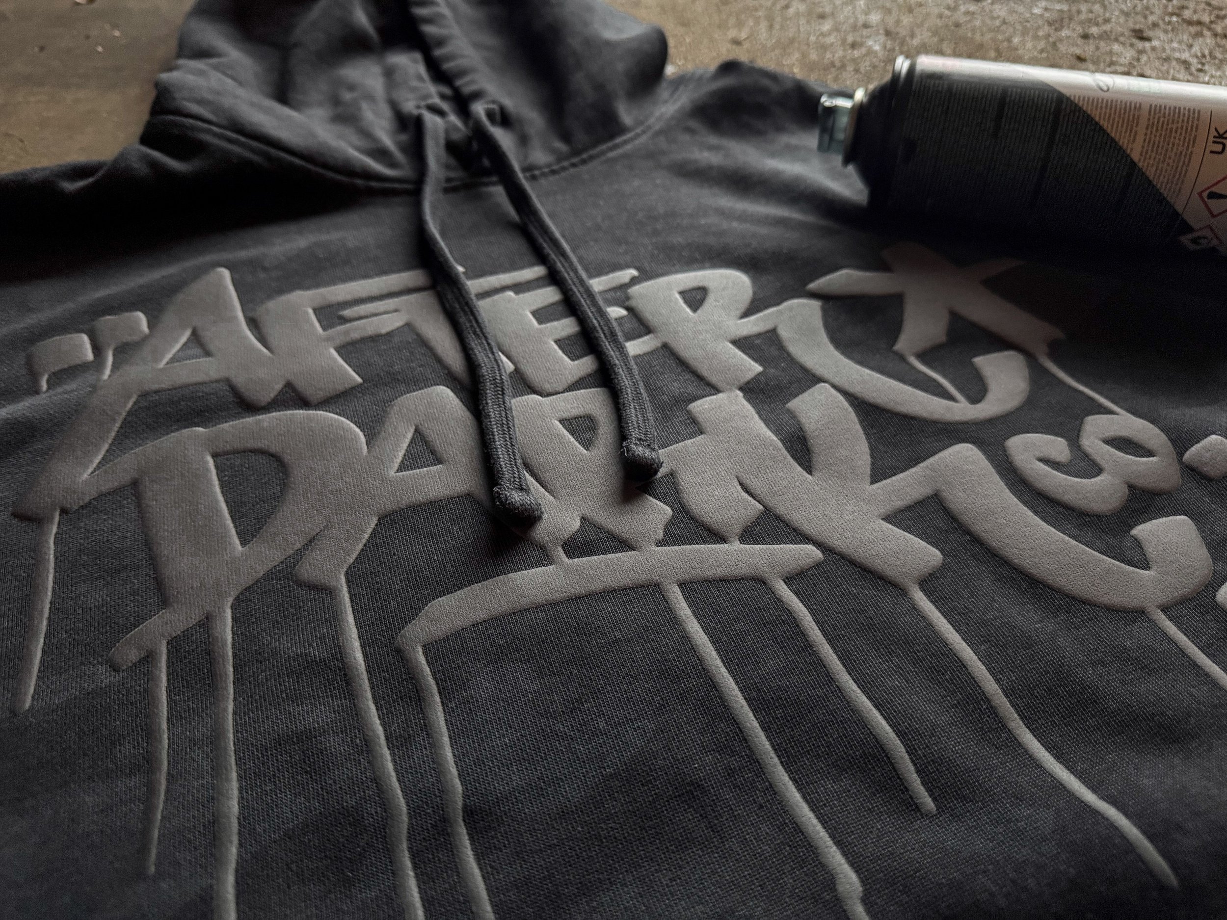 Raised Black Puff lettering uses texture and dimension to separate a tonal design from a black camo hoodie.