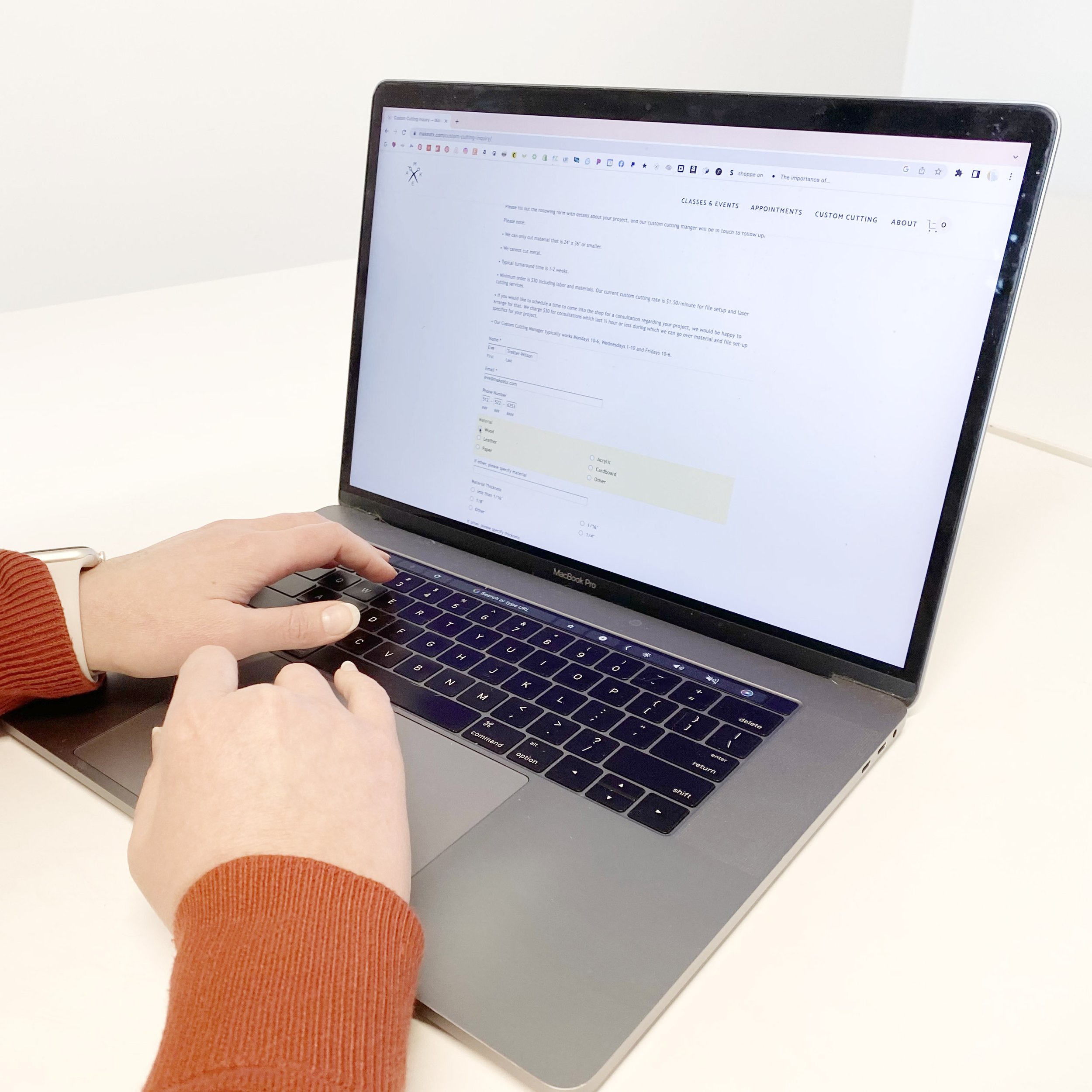 Hands on laptop with custom cutting inquiry form visible on screen.