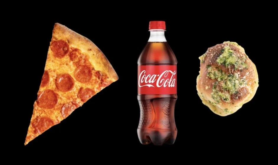 A slice of pepperoni pizza, a Coca-Cola bottle, and a cookie with green frosting on a black background.