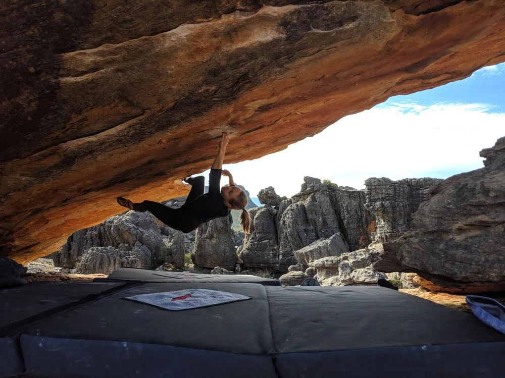 Amy in her preferred environment, upside down, on Roof is On Fire (V6), Rocklands, South Africa. Gordon Fowler