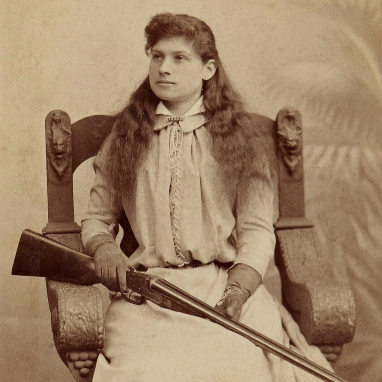 Archival photo of Annie Oakley holding her favorite double barrel shotgun. Circa 1880.